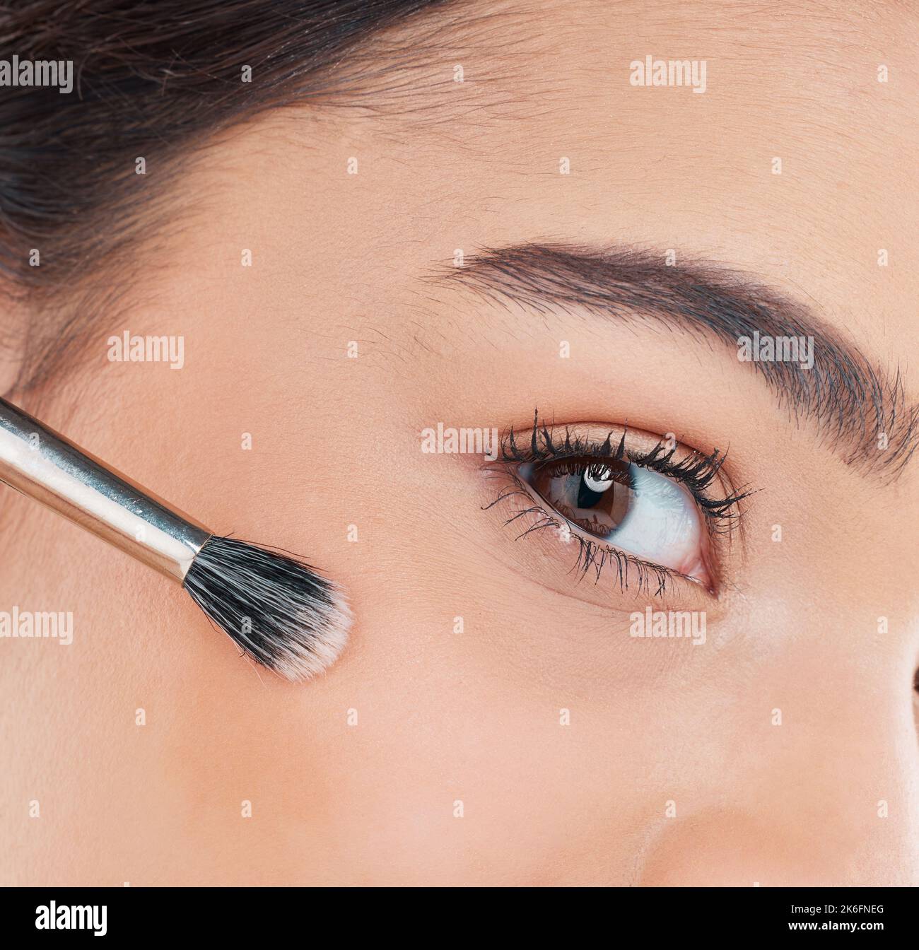 Un pennello per frullare. Ritratto corto di una giovane donna attraente in posa in studio su uno sfondo grigio. Foto Stock