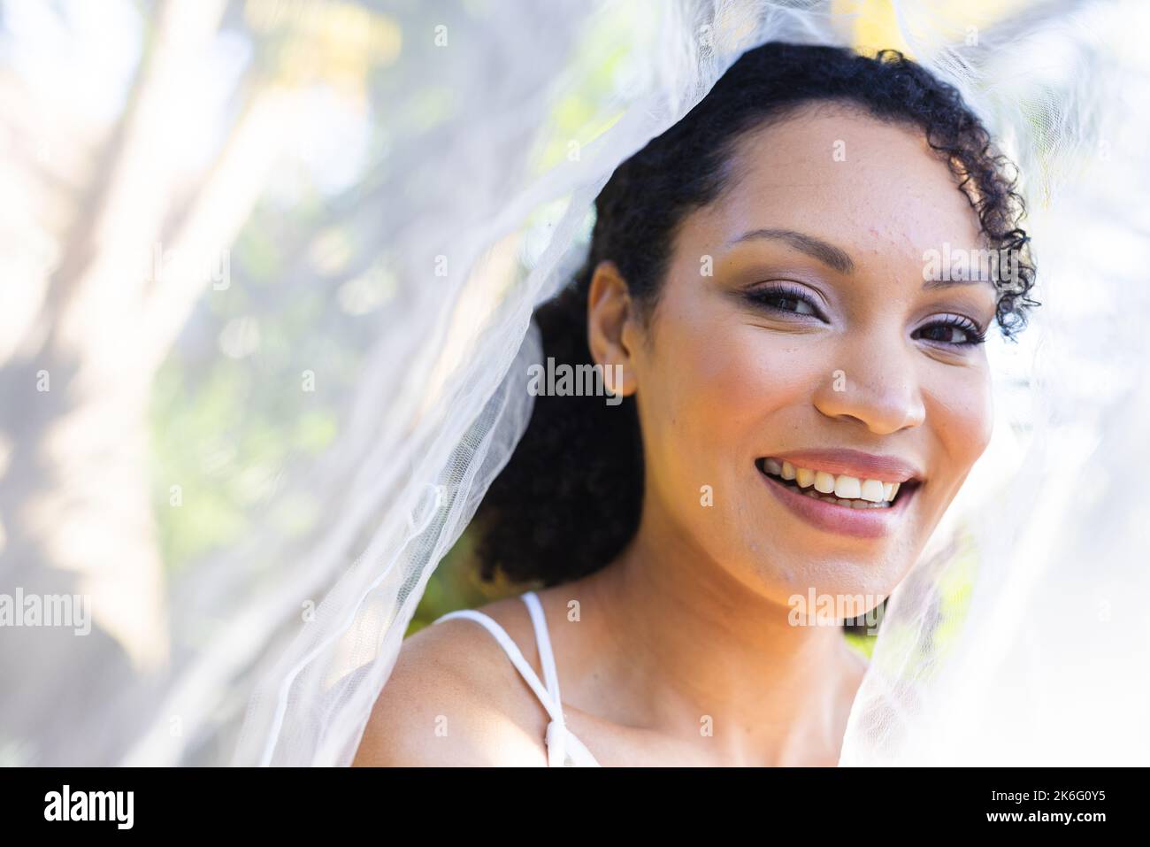 Ritratto di felice ragazza afro-americana che indossa abiti da sposa e velo durante il giorno del matrimonio Foto Stock