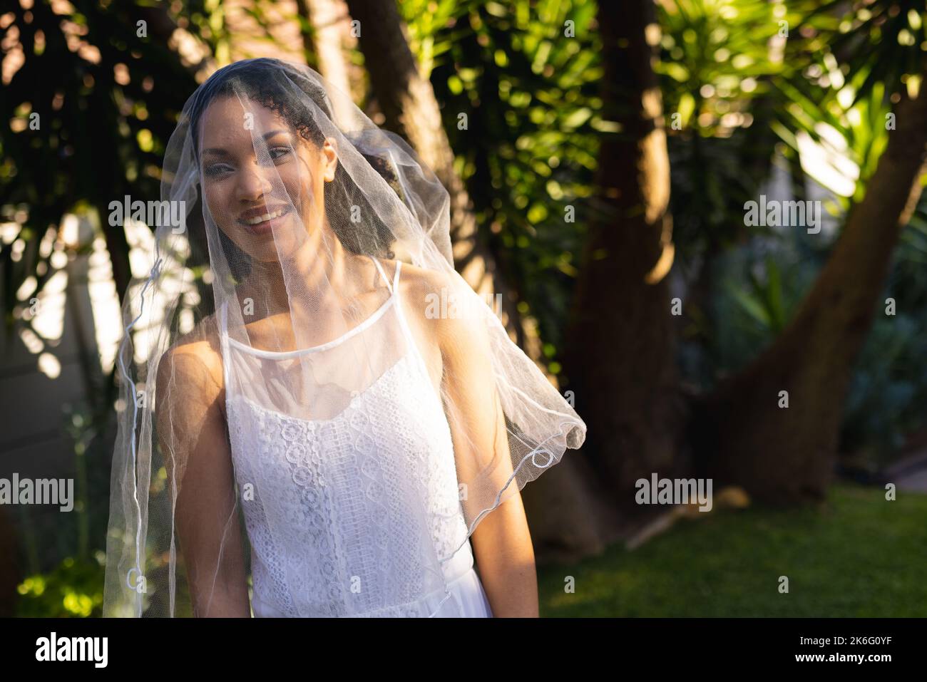 Donna afro-americana felice che indossa abiti da sposa e velo durante il giorno del matrimonio Foto Stock
