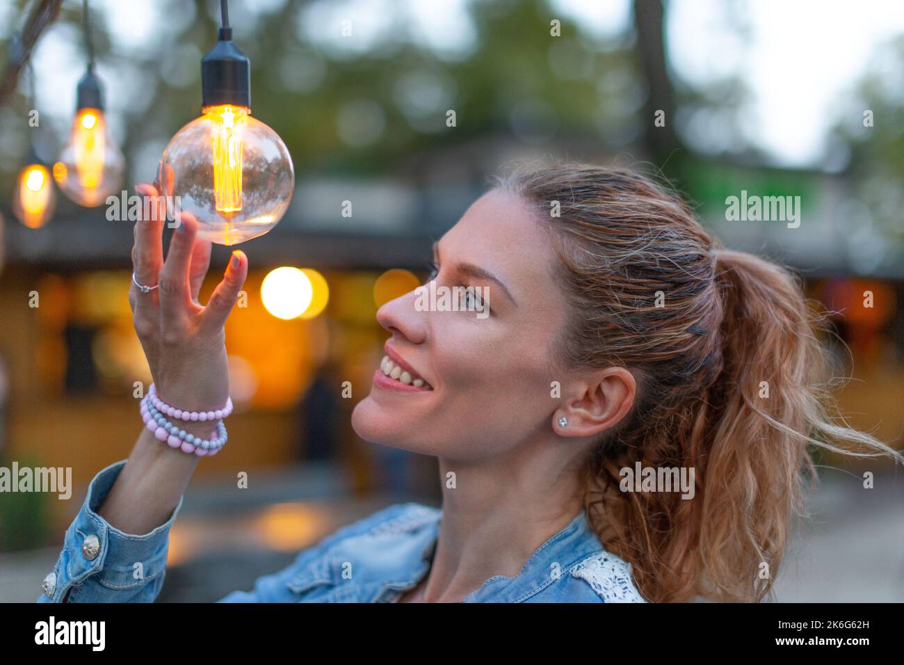 Giovane donna caucasica che tiene una lampadina a LED ad alta efficienza energetica all'aperto Foto Stock