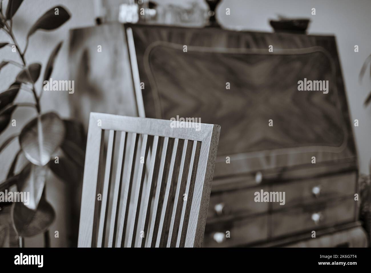 Immagine interna di una sedia in legno di faggio che passa dalla nitidezza alla sfocatura con un antico segretario fuori fuoco sullo sfondo. Foto Stock