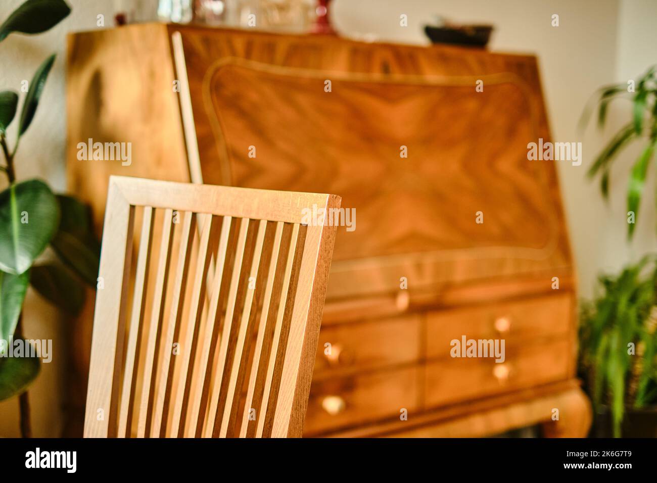 Immagine interna di una sedia in legno di faggio che passa dalla nitidezza alla sfocatura con un antico segretario fuori fuoco sullo sfondo. Foto Stock