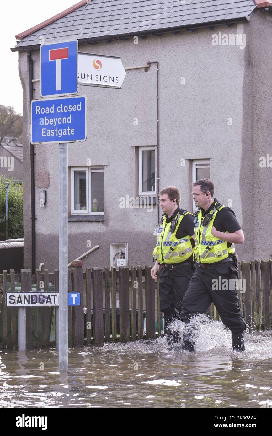 Kendal, Cumbria - 6th 2015 dicembre - gli ufficiali della polizia della Cumbria camminano attraverso l'acqua delle inondazioni a Sandgate a Kendal, Cumbria il 6th dicembre 2015 per aiutare i residenti colpiti dalle inondazioni di Storm Desmond. PIC Credit: Scott CM/Alamy Live News Foto Stock