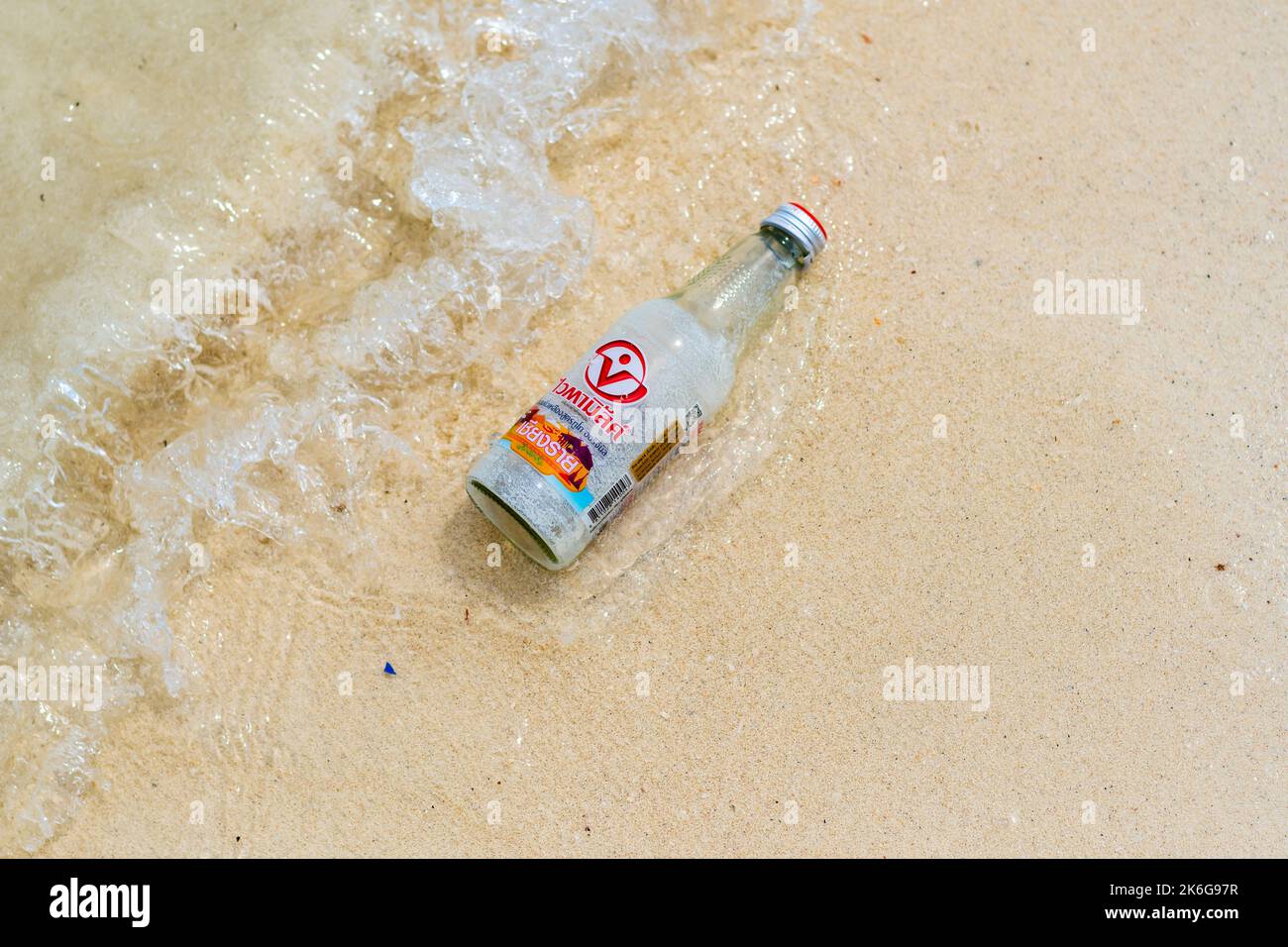 Koh Lipe, Thailandia - 13.11.2019: Bicchiere vuoto da limonata drink è posto sulla spiaggia di sabbia vicino al mare, a Ko Lipe isola, Thailandia. Immondizia di vetro Foto Stock