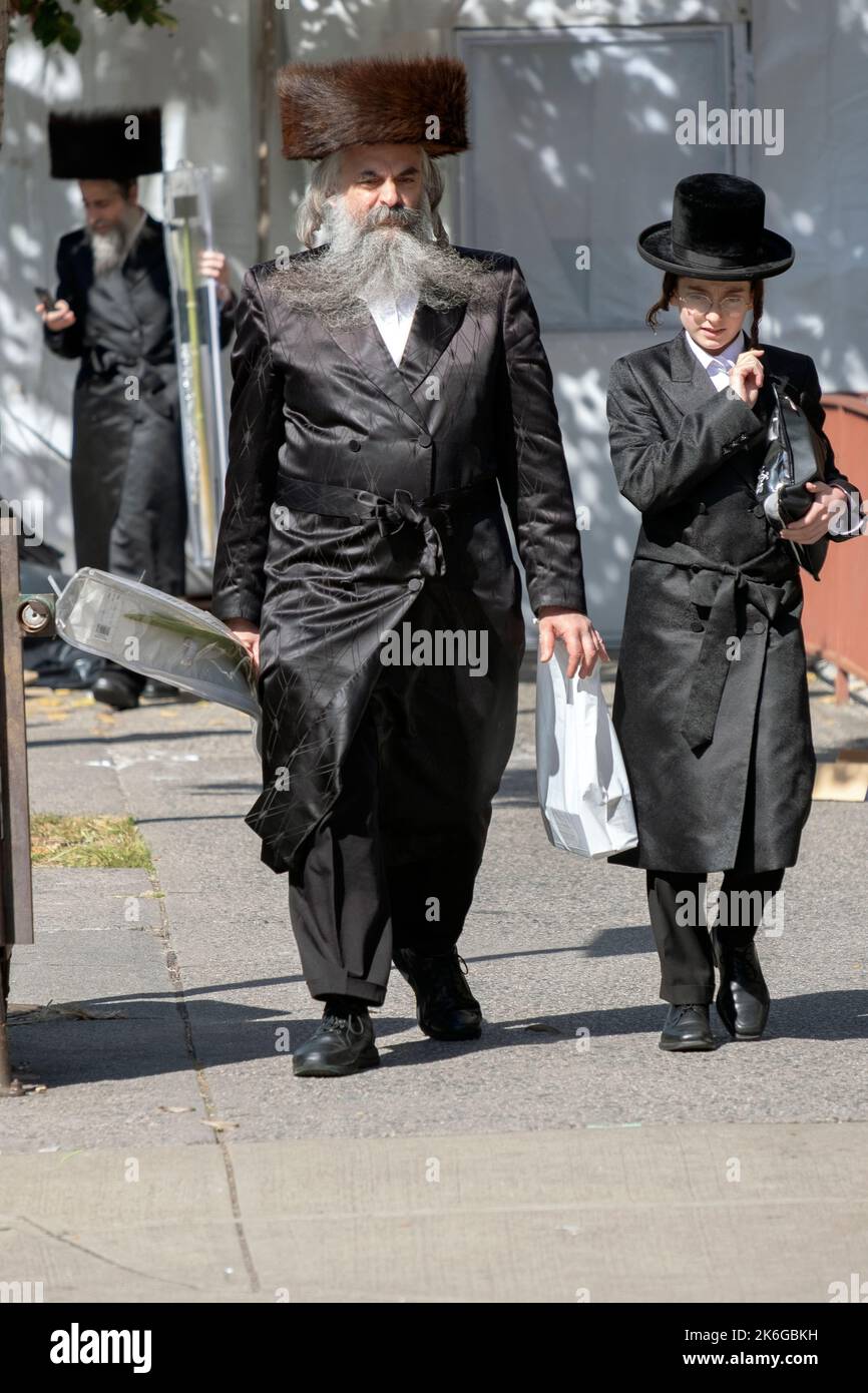 Su Sukkos, un uomo ortodosso ritorna dai servizi mattutini con, presumibilmente, suo figlio o nipote. Su Lee Avenue a Brooklyn, New York. Foto Stock