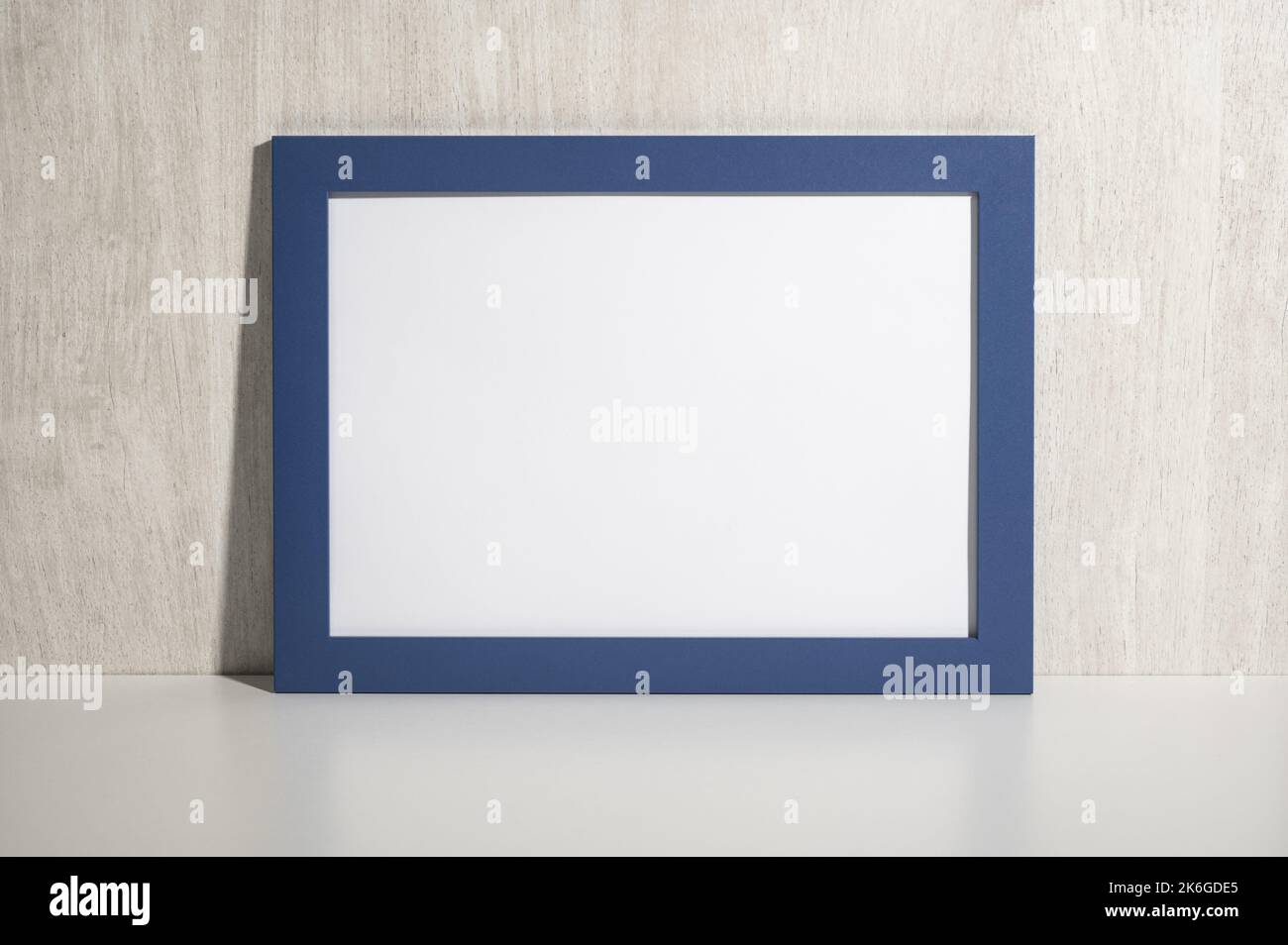 Cornice blu orizzontale mockup su ripiano bianco, tavolo. Diploma mockup. Certificato, diploma, foto, ringraziamento blu blank frame mockup. Legno bianco wal Foto Stock