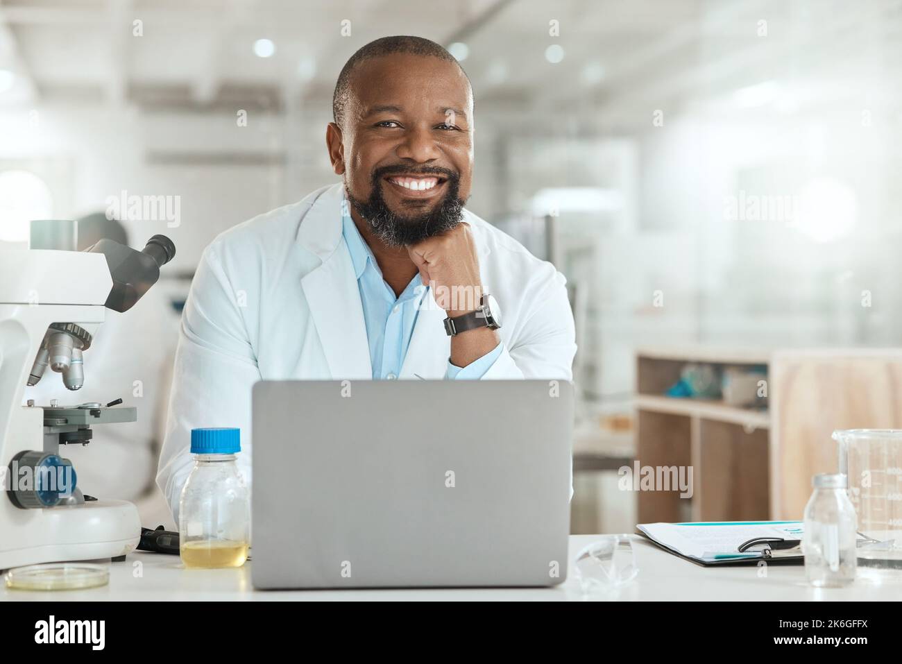 È una giornata intensa nei laboratori. un bel scienziato maturo seduto da solo nel suo laboratorio e utilizzando il suo computer portatile. Foto Stock