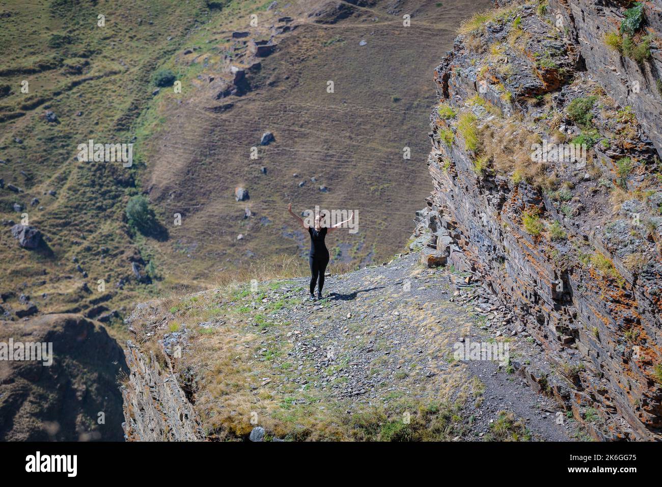 Ragazza in montagna guarda la telecamera a braccia aperte Foto Stock