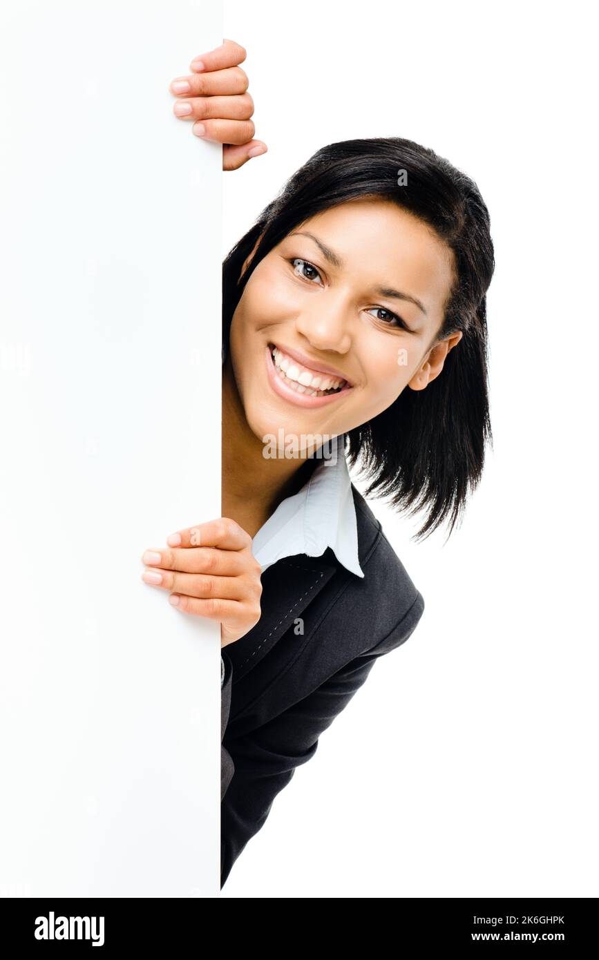 Peeking fuori da dietro le pagine. una giovane donna d'affari da dietro un cartello bianco su uno sfondo studio. Foto Stock