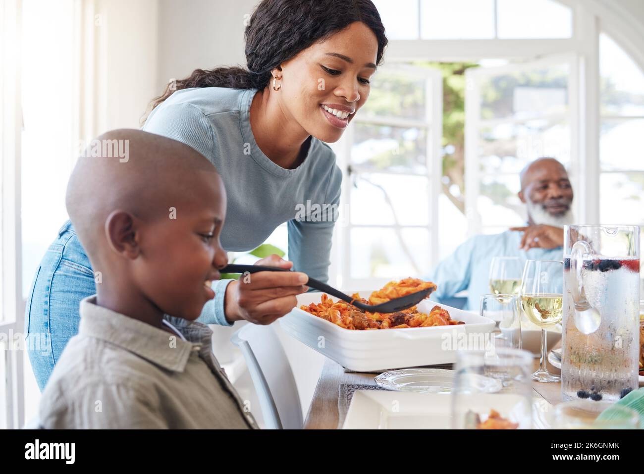 Una famiglia amorevole può essere qualsiasi famiglia. una madre che mangia per suo figlio a casa. Foto Stock