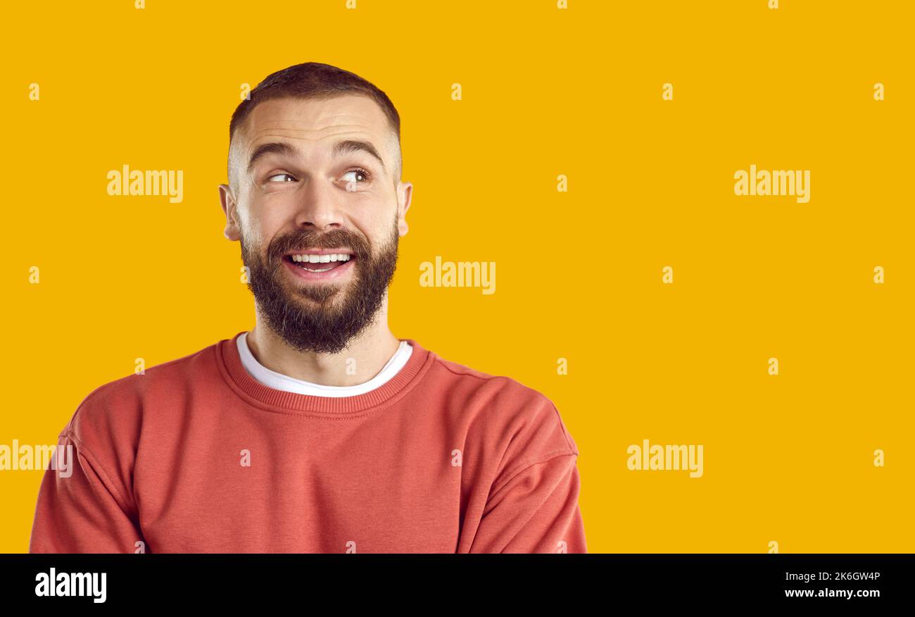 Felice giovane uomo allegro bearded che cerca di copiare lato spazio su sfondo giallo Foto Stock