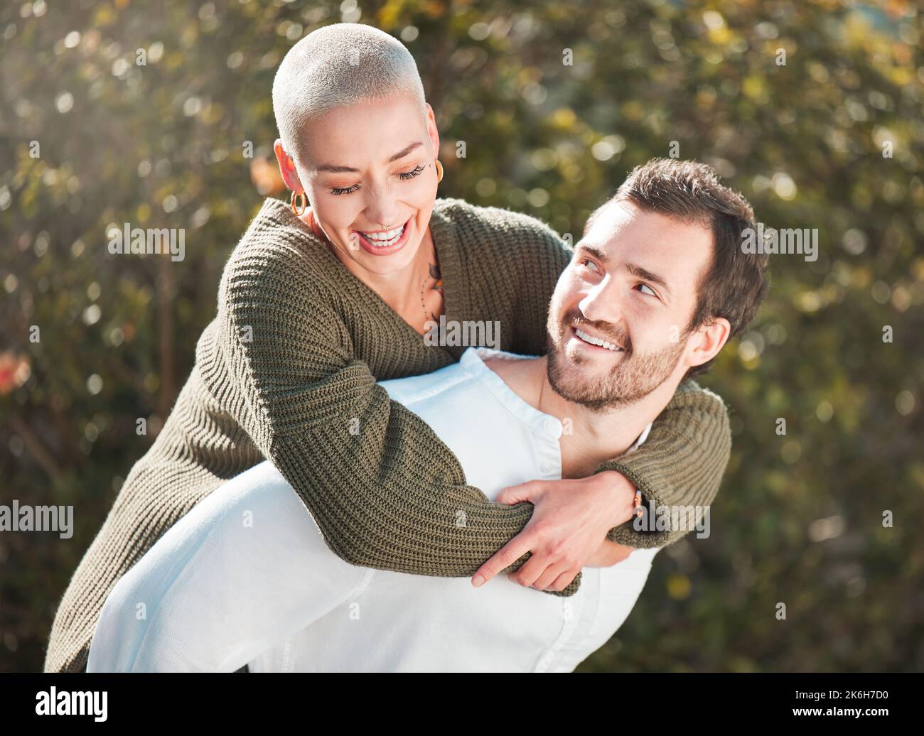 Shell ha sempre la schiena. un bel giovane uomo piggybacking sua moglie all'aperto. Foto Stock