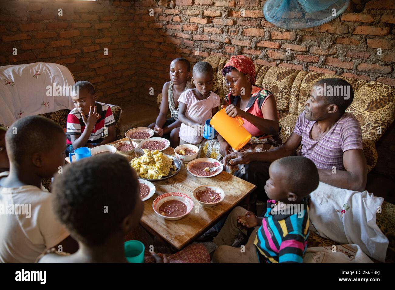 Famiglia ugandese che condivide un pasto a base di fagioli e purè di banane saporite nella loro casa nel distretto di Kasese, Uganda, Africa orientale. Foto Stock