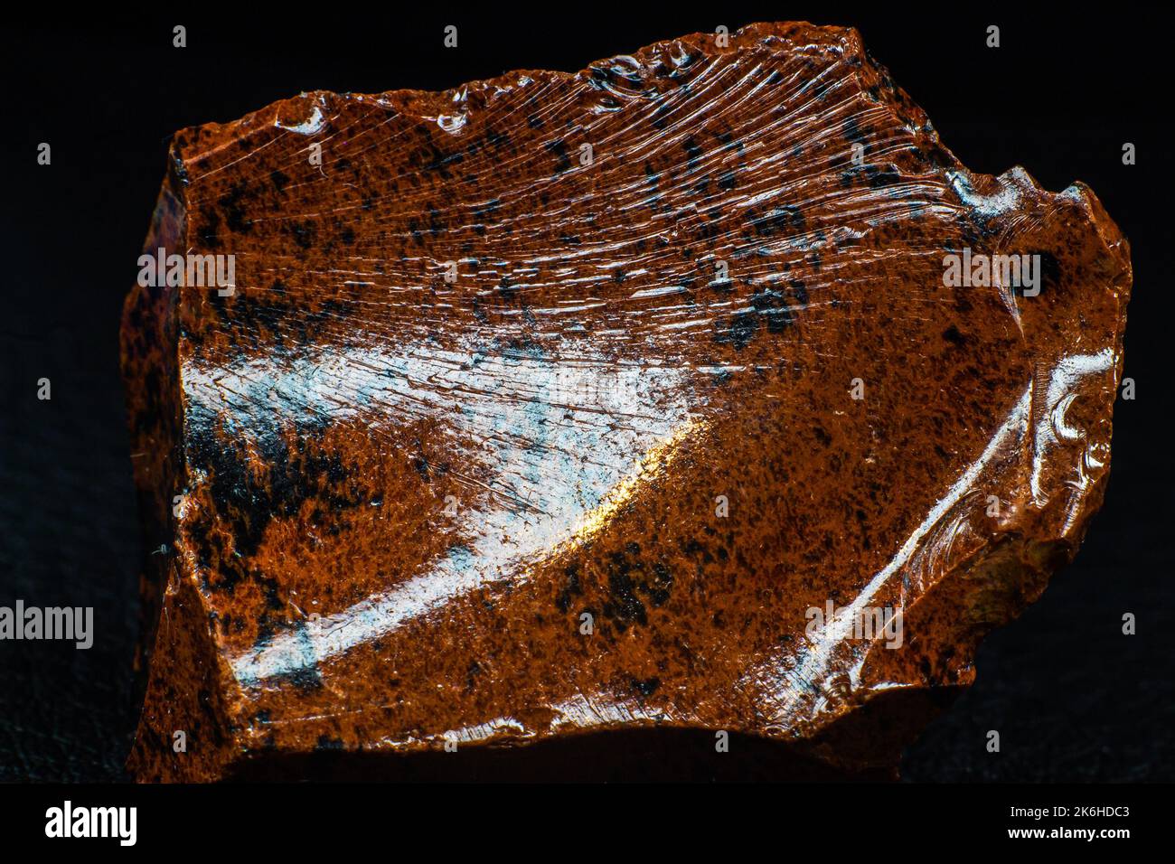 Autentico esemplare lucido di macrogano arancione pietra vulcanica ossidiana macro isolato su fondo in pelle nera Foto Stock