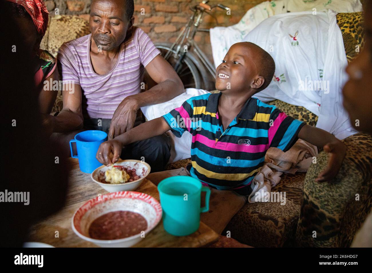 Famiglia ugandese che condivide un pasto a base di fagioli e purè di banane saporite nella loro casa nel distretto di Kasese, Uganda, Africa orientale. Foto Stock