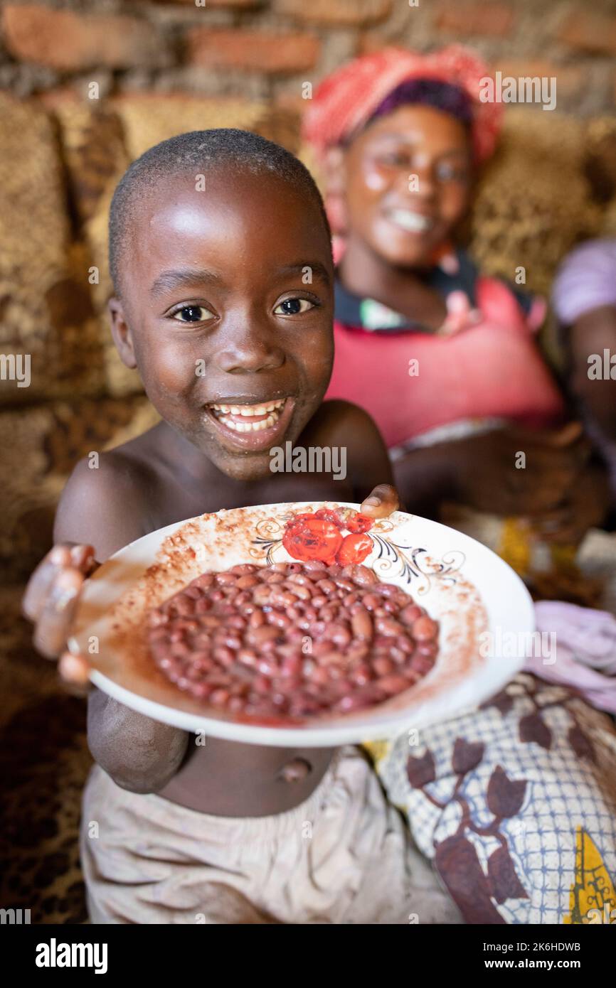 Famiglia ugandese che condivide un pasto di fagioli nella loro casa nel distretto di Kasese, Uganda, Africa orientale. Foto Stock