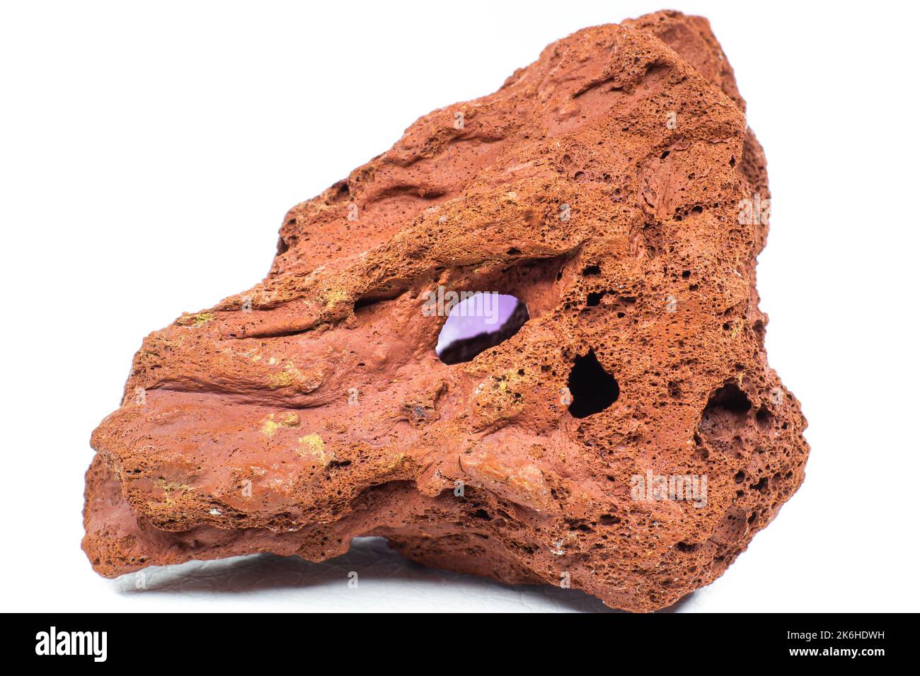 Rosso ruvido pietra lavica macro focalizzata e isolata su superficie bianca macro isolata Foto Stock