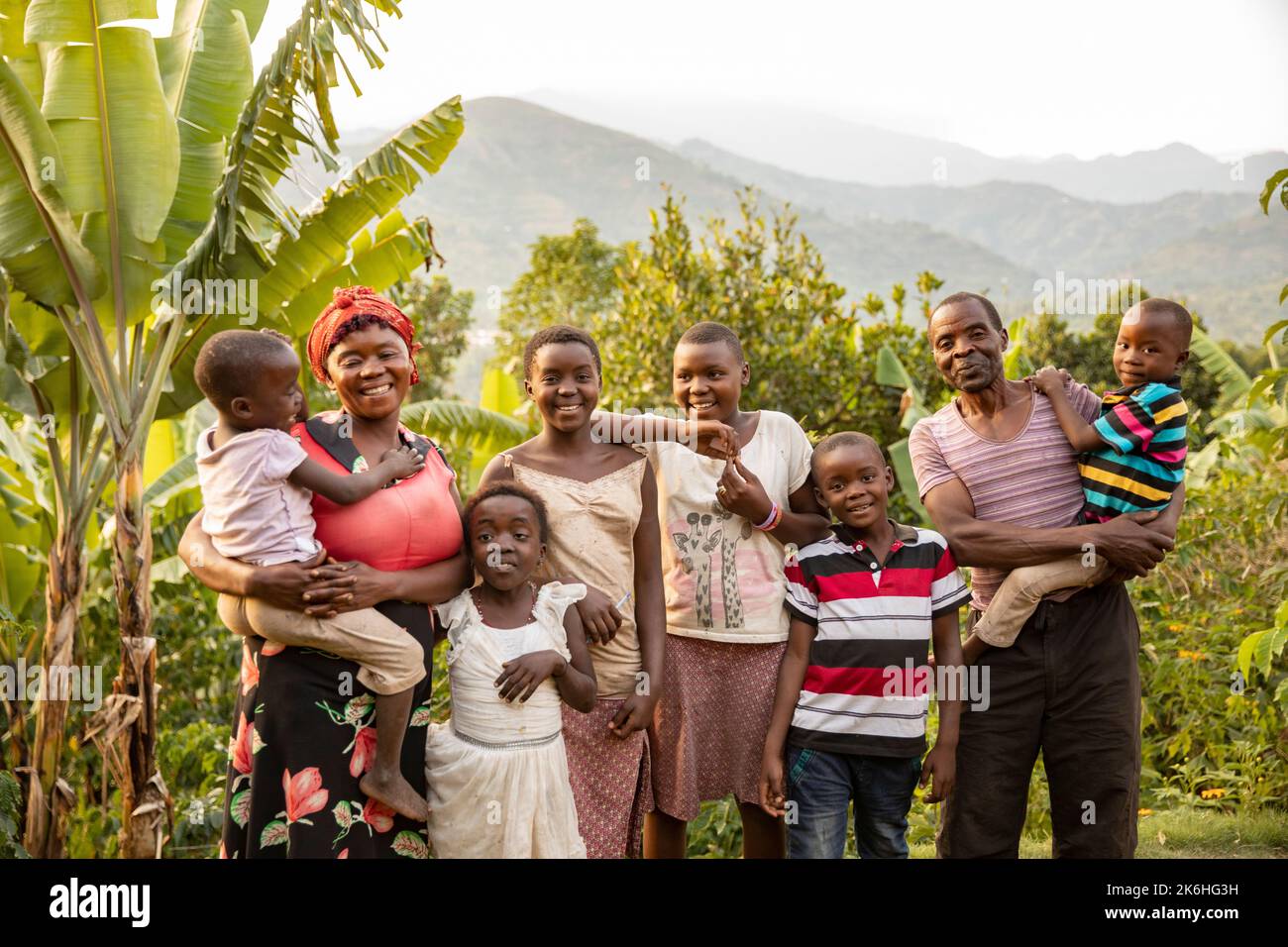 Una madre e un padre stanno insieme ai loro sei figli fuori dalla loro casa, nei Monti Rwenzori, nell'Uganda occidentale, in Africa orientale. Foto Stock
