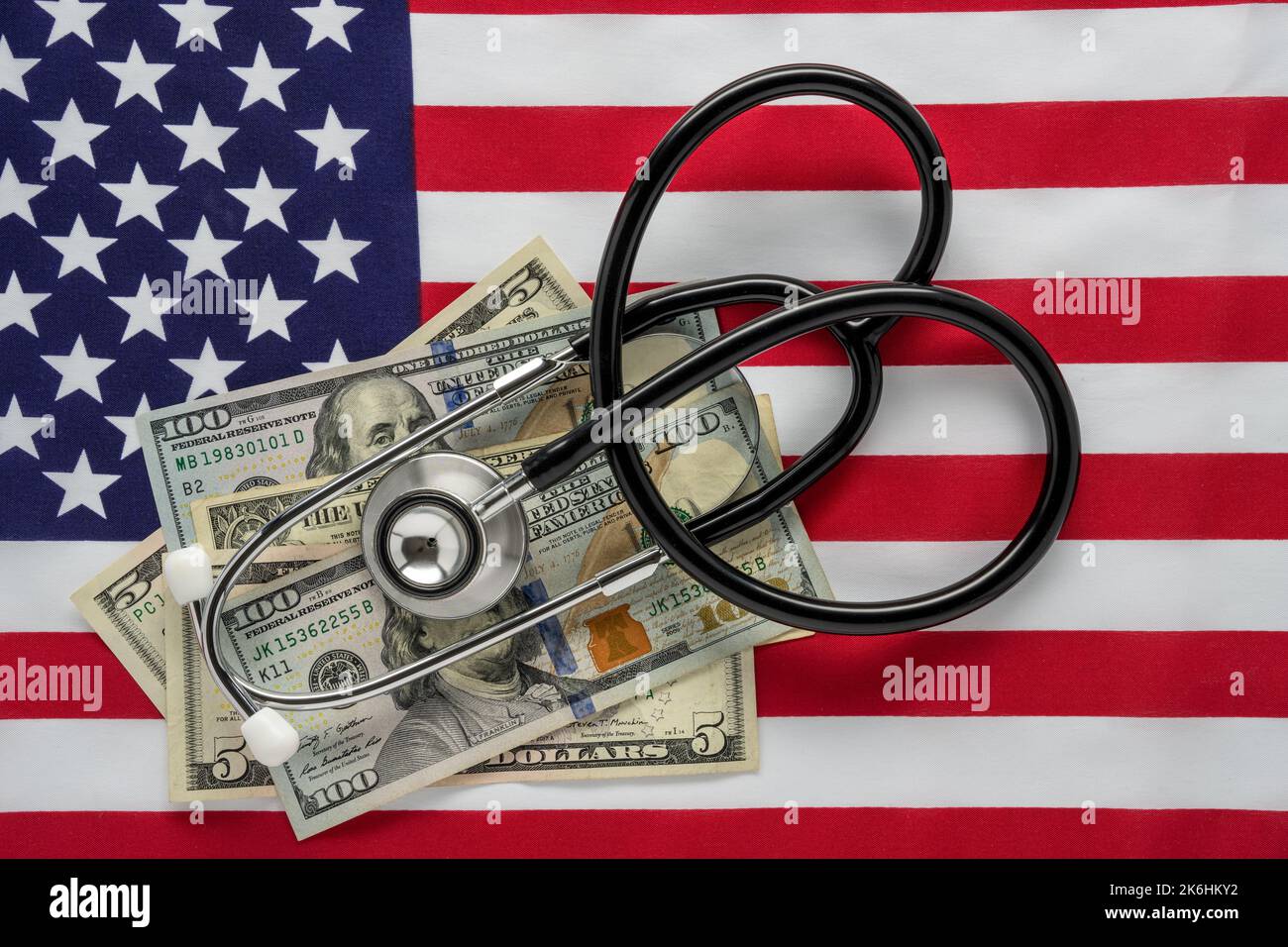 Bandiera degli Stati Uniti con fatture da 100 e 5 e 1 dollari e uno stetoscopio per i concetti di salute dell'economia e costo della sanità Foto Stock