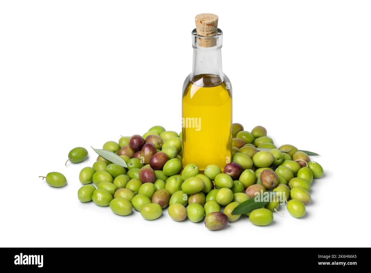 Olio d'oliva in bottiglia circondato da olive verdi fresche e crude isolate su fondo bianco Foto Stock