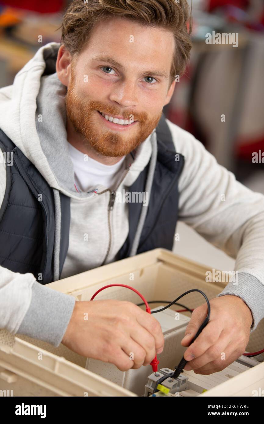 un elettricista sorridente che ripara la scatola elettrica Foto Stock