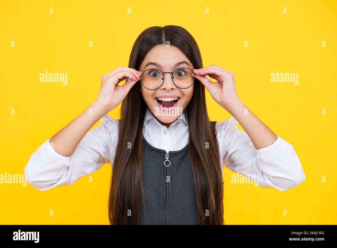 Ragazza cute scuola che indossa gli occhiali su sfondo giallo studio, intelligente studentessa intelligente in occhiali. Studente nerd, scolarista genio, Scuola Foto Stock