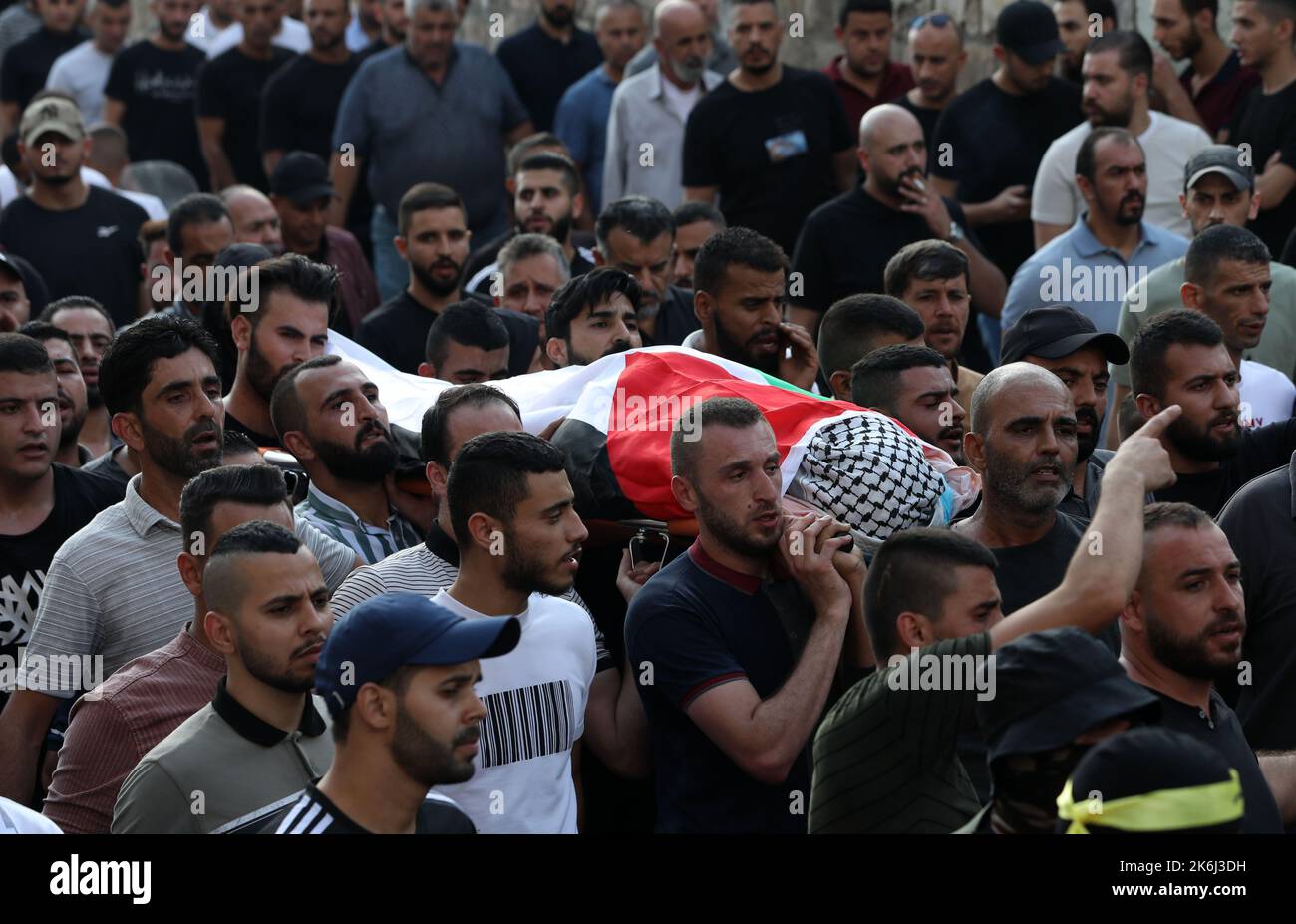 Jenin. 14th Ott 2022. I lutto portano il corpo di un medico palestinese ucciso dai soldati israeliani durante i suoi funerali nella città di Jenin, in Cisgiordania, il 14 ottobre 2022. Il medico palestinese, gravemente ferito dai soldati israeliani durante gli scontri tra palestinesi e soldati israeliani venerdì nella città di Jenin, nella sponda nord occidentale, è morto per le sue ferite, ha affermato il ministero della sanità palestinese. Credit: Yayman Nobani/Xinhua/Alamy Live News Foto Stock