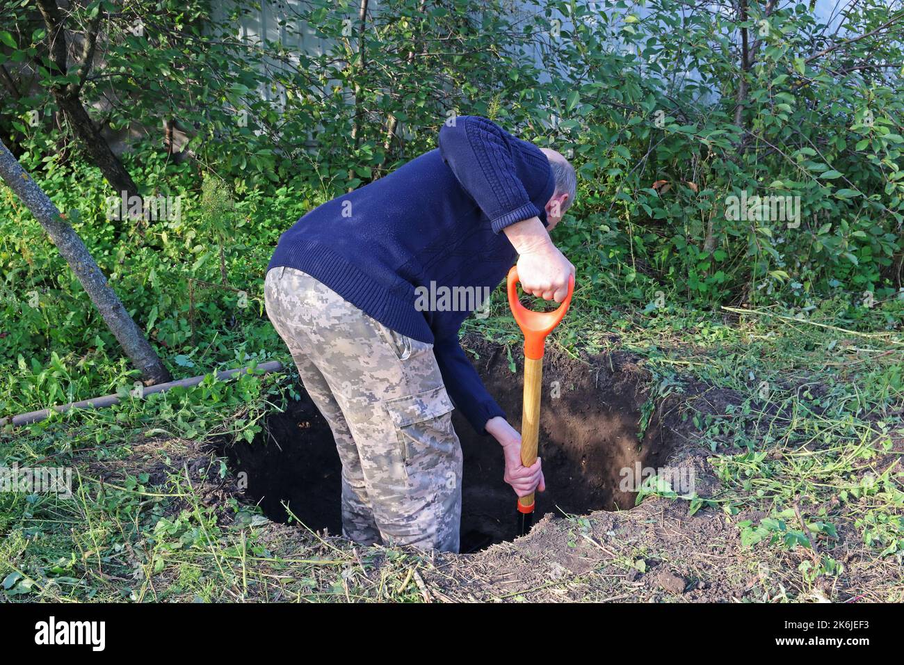L'uomo scava una buca profonda. L'uomo si riposa dopo il lavoro. Scavando una buca da pala. Foto Stock