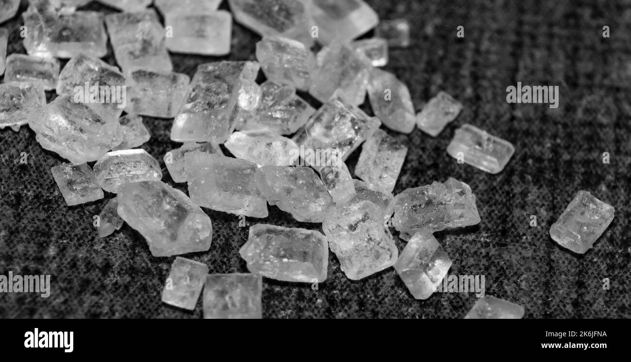 Macro immagine dei cristalli di zucchero bianco su sfondo nero e messa a fuoco selettiva. Immagine ravvicinata dei chicchi di zucchero bianco. Foto Stock