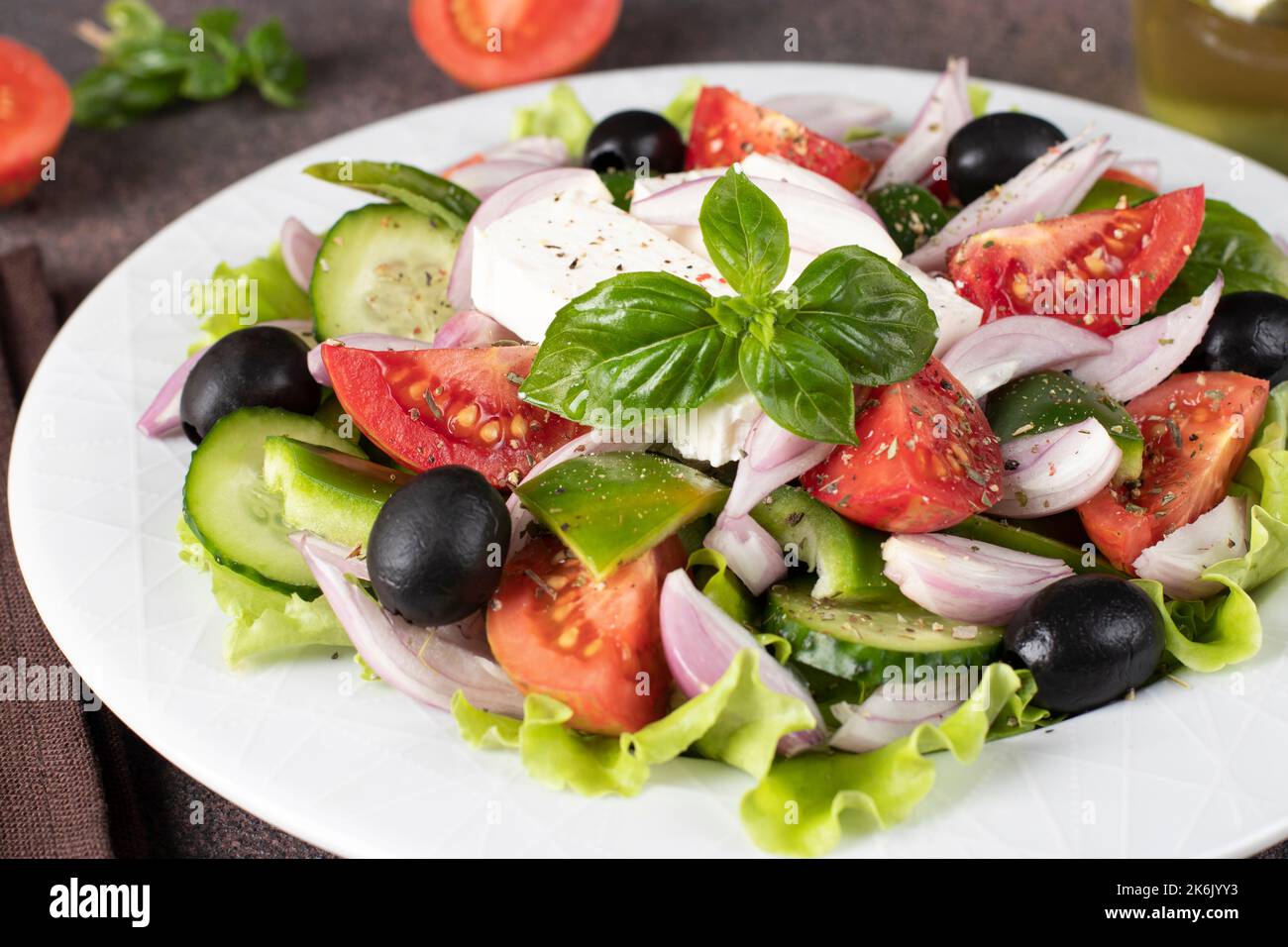 Insalata greca classica di pomodori, cetrioli, peperoni dolci, olive, basilico e feta su piatto bianco Foto Stock