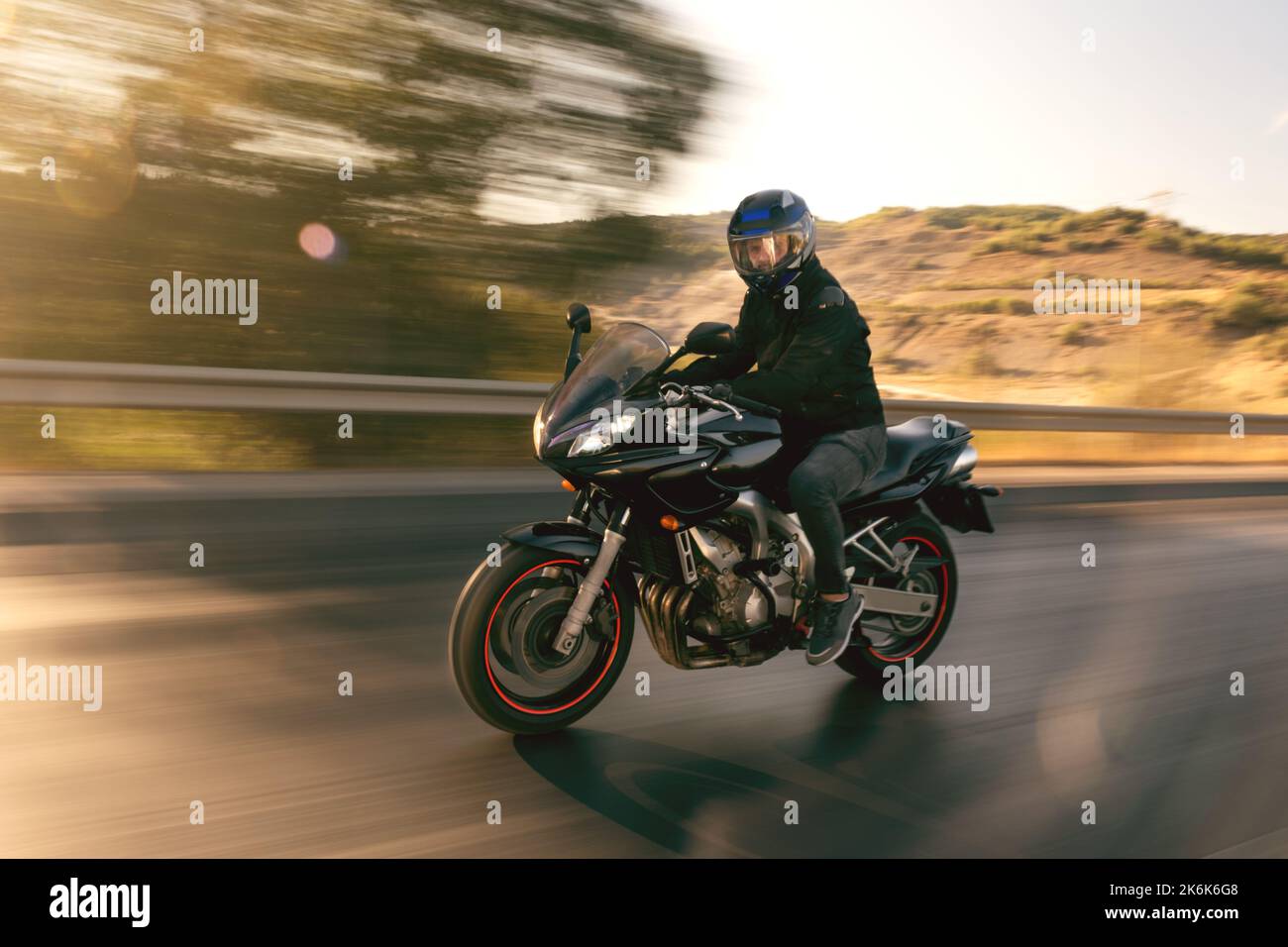 Vista laterale di un motociclista che guida in autostrada con sfocatura del movimento. Foto Stock