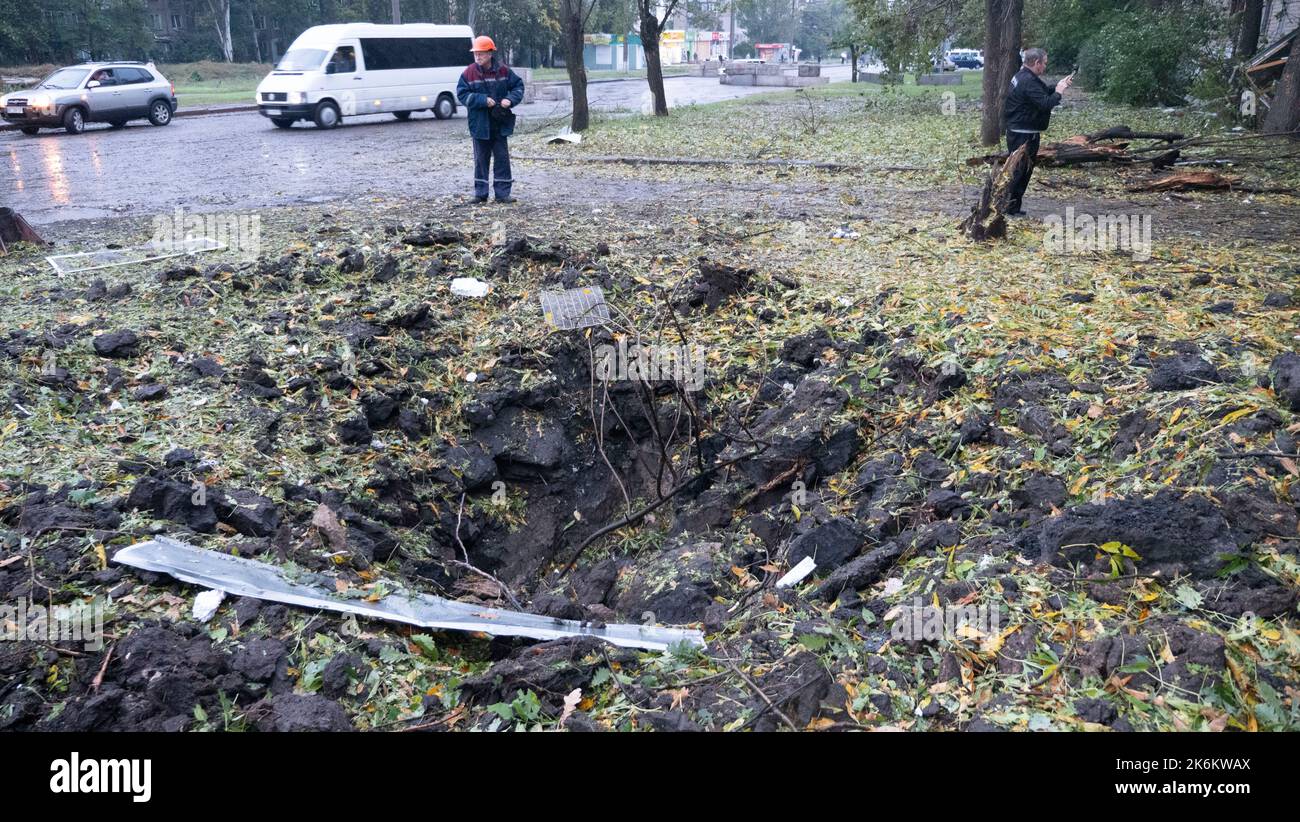 La gente guarda un edificio danneggiato dopo uno sciopero missilistico russo. Foto Stock