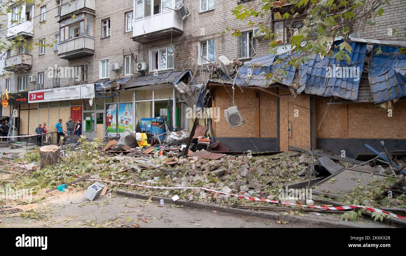 La gente si trova vicino a un edificio di appartamenti che è stato distrutto dopo uno sciopero missilistico. Foto Stock