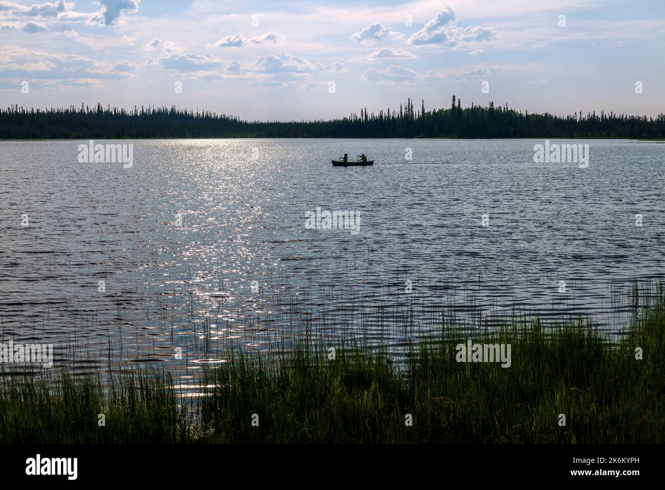 Due adulti pagaiano una canoa al tramonto sul lago Deadman; il campeggio sul lago Deadman; la riserva naturale Tetlin National Wildlife Refuge; Alaska; USA Foto Stock