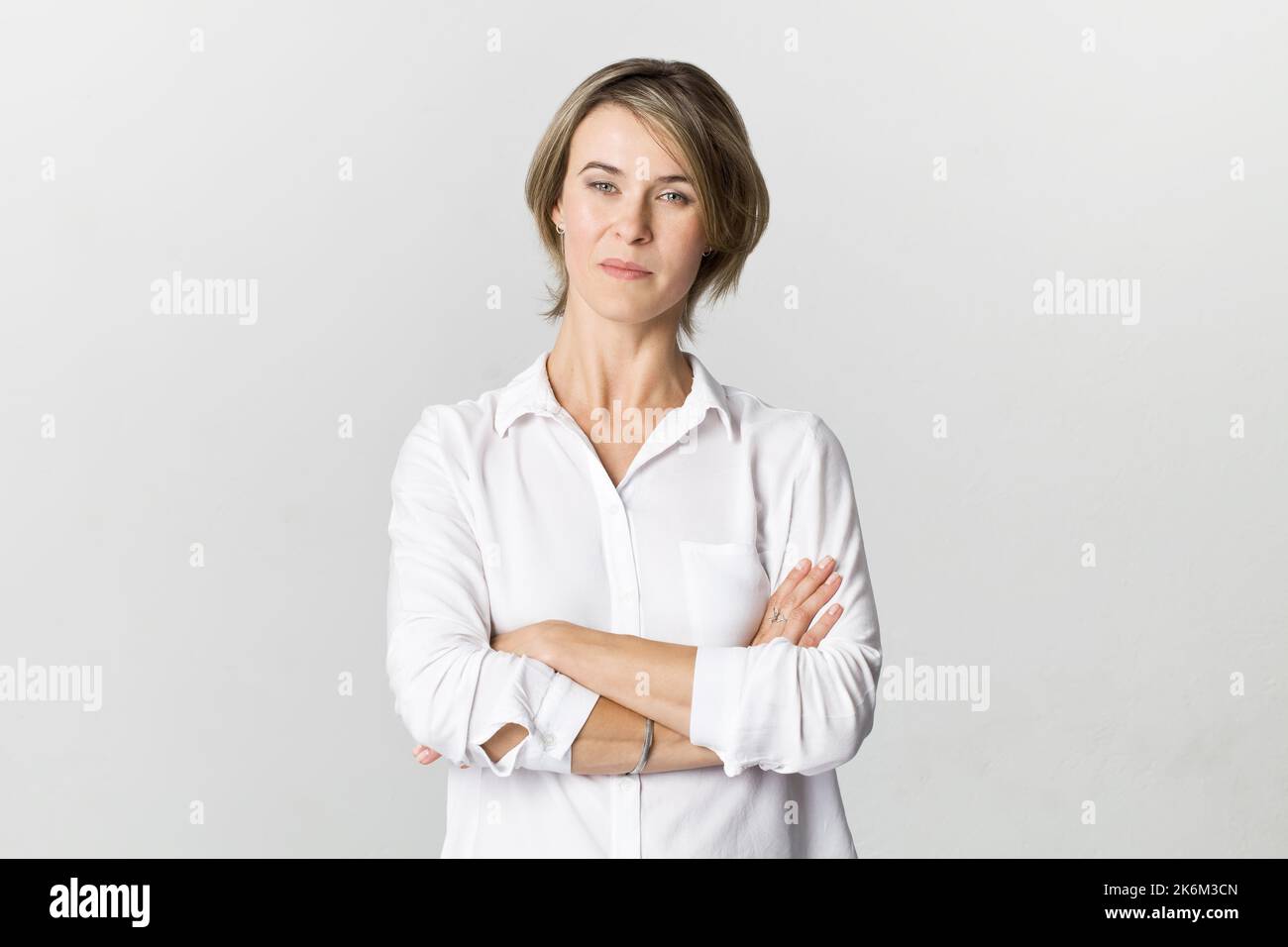 Seria donna d'affari in camicia bianca ritratto contro parete bianca Foto Stock