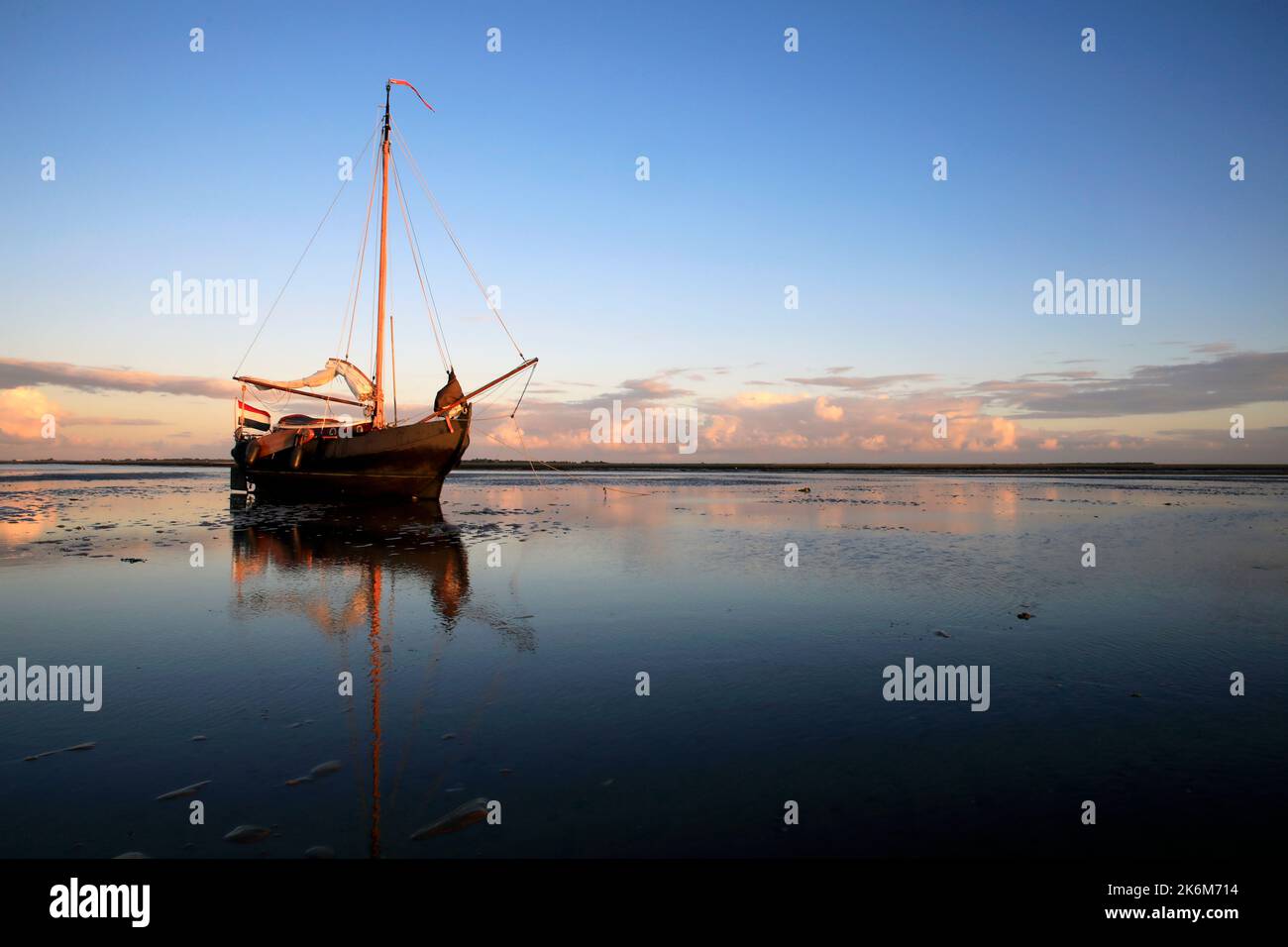 Una classica barca a vela adagiata sulle maree del Mare di Wadden, Olanda Foto Stock