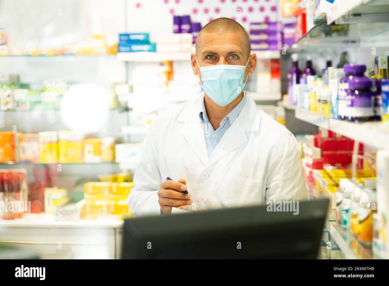 Ritratto del farmacista in maschera medica lavorando al registratore di cassa in farmacia Foto Stock