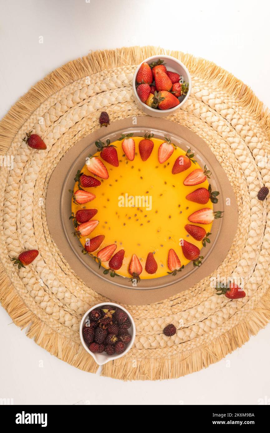 cheesecake al frutto della passione decorata con fragole e more fresche su un tavolo pronto a mangiare, dolce in studio, decorazione piatto Foto Stock