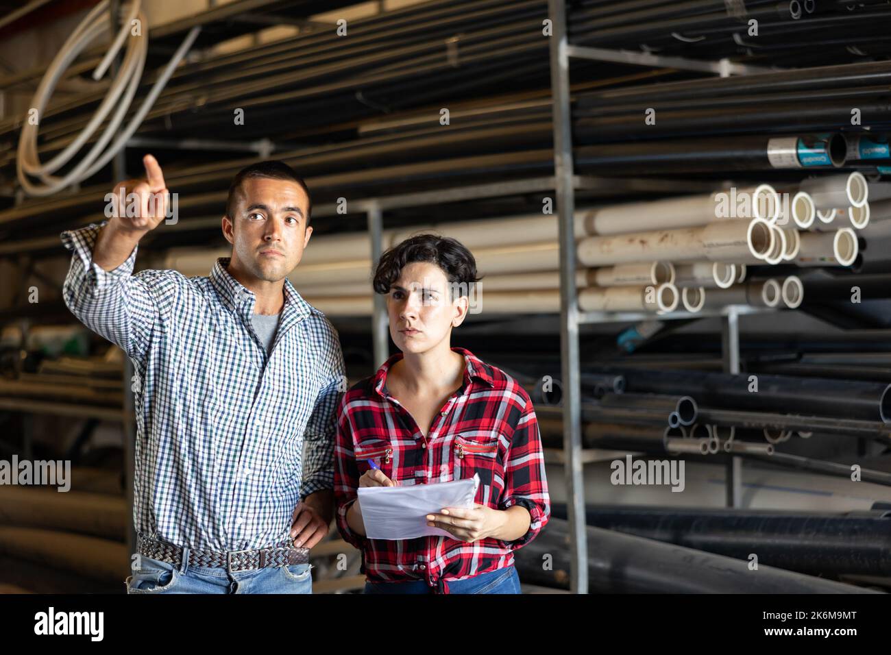 Uomo e donna insieme effettuano contabilità e inventario in un magazzino di materiali da costruzione Foto Stock