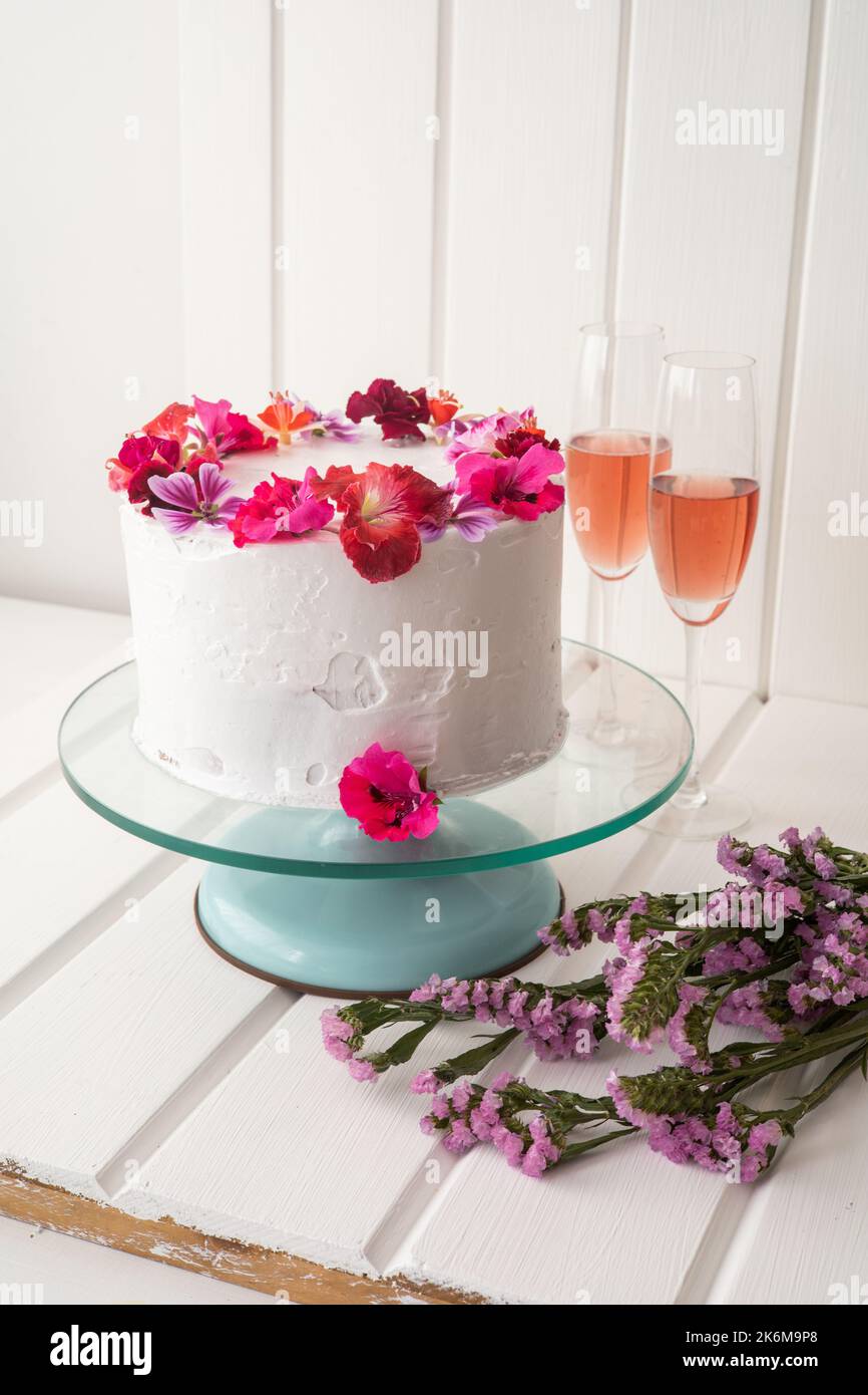 dettagli della decorazione della torta con crema e fiori naturali  commestibili, insieme a due bicchieri di champagne, dolci per dessert Foto  stock - Alamy