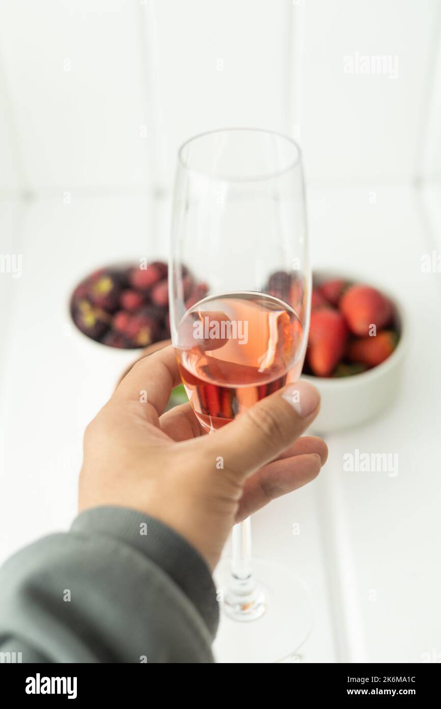 con un bicchiere di champagne freddo e sullo sfondo frutta fresca, fragole e more, cibo sano e dieta in studio Foto Stock