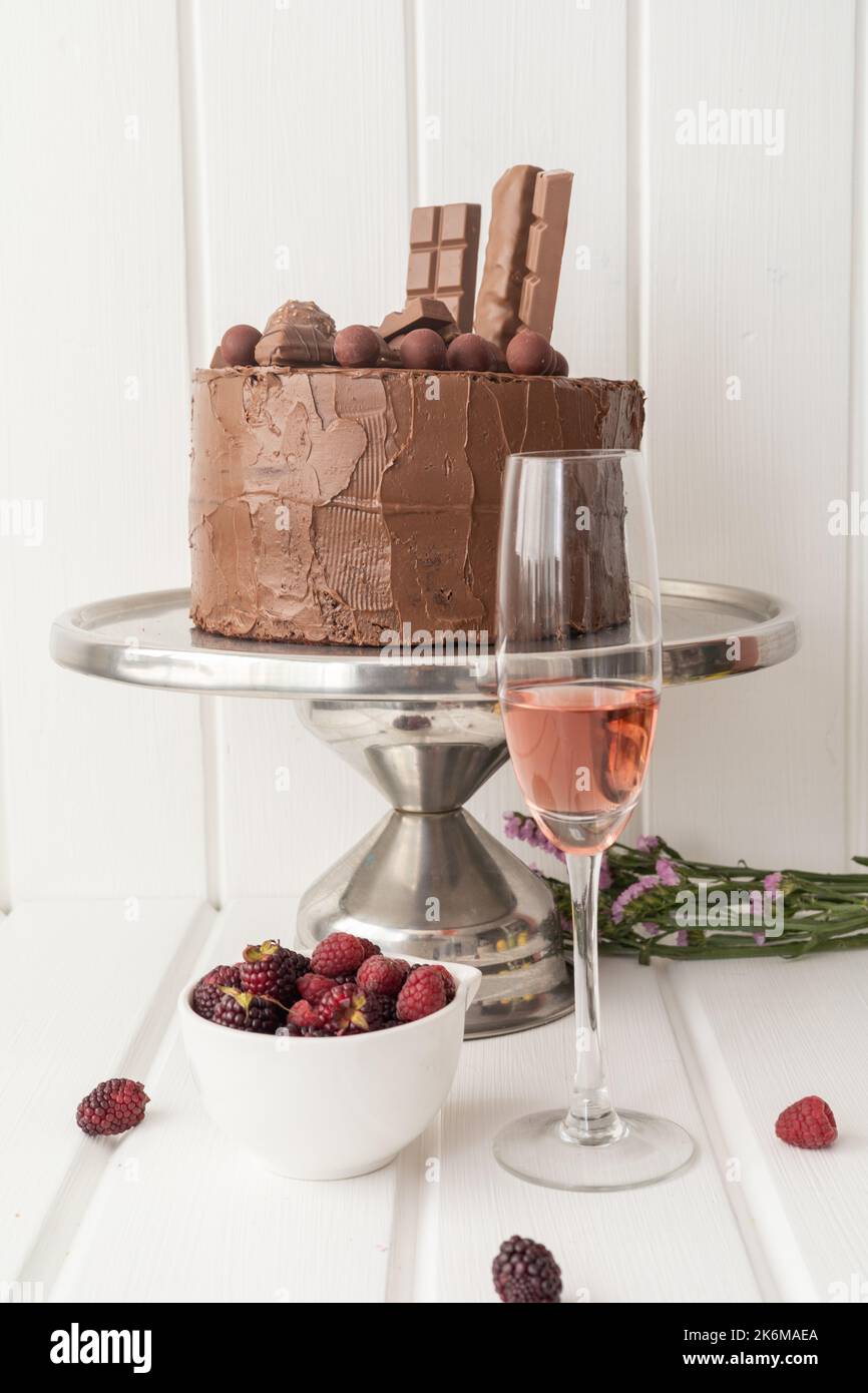 foto studio con cibo e bevande decorate per festeggiare, deliziosa torta al cioccolato, frutta e un bicchiere pieno, pasticceria e stile di vita Foto Stock