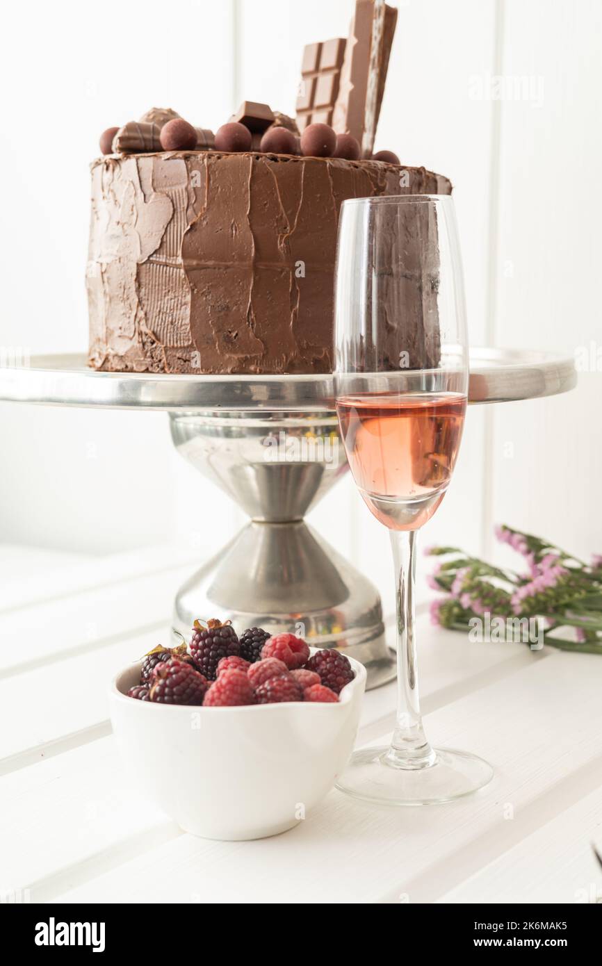 foto studio con cibo e bevande decorate per una celebrazione elegante, bella torta al cioccolato, frutta e un bicchiere pieno Foto Stock