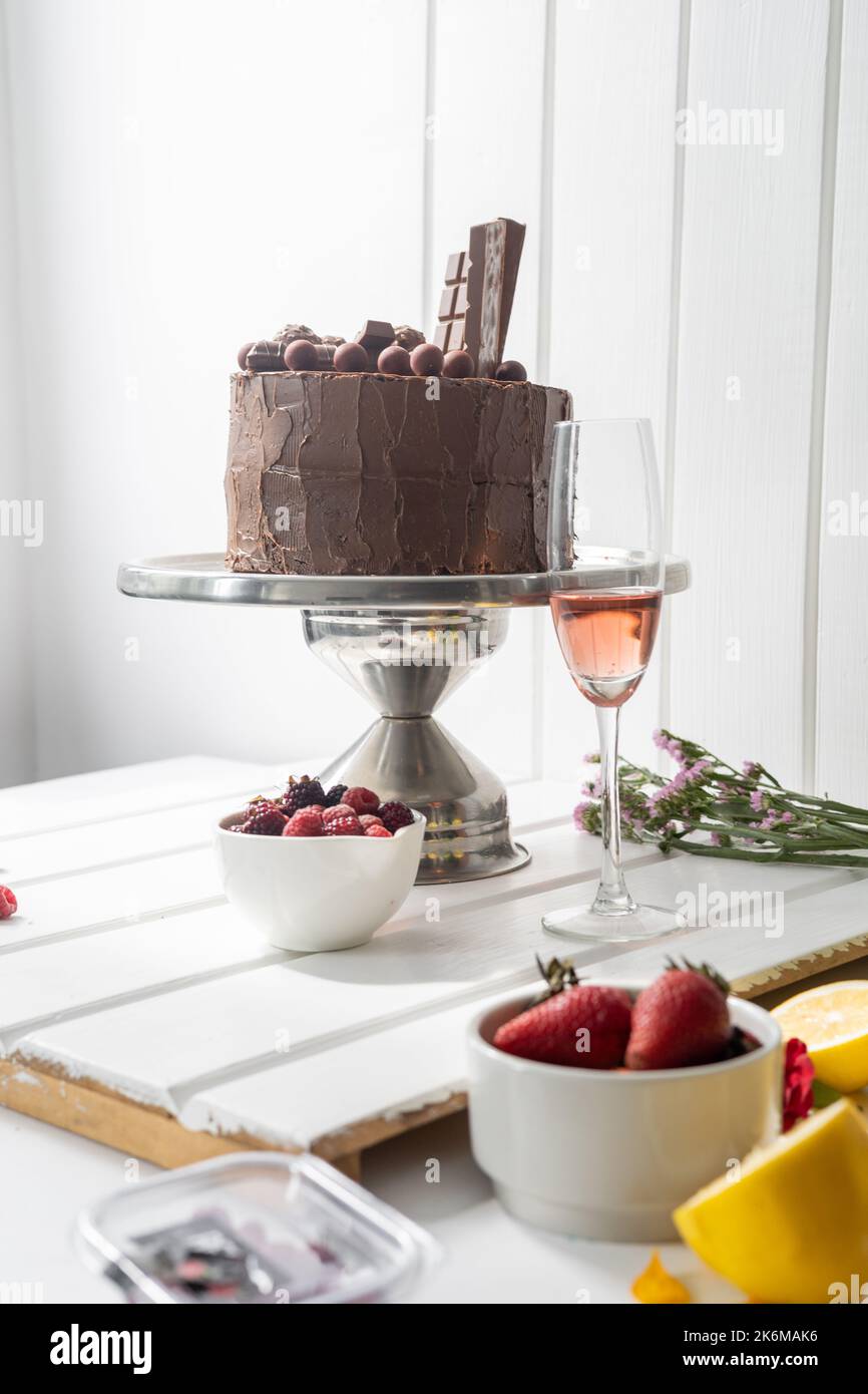 elegante decorazione da tavolo gourmet con torta al cioccolato, frutta e un bicchiere di champagne, dessert con bevanda per la celebrazione, dolci voglie Foto Stock