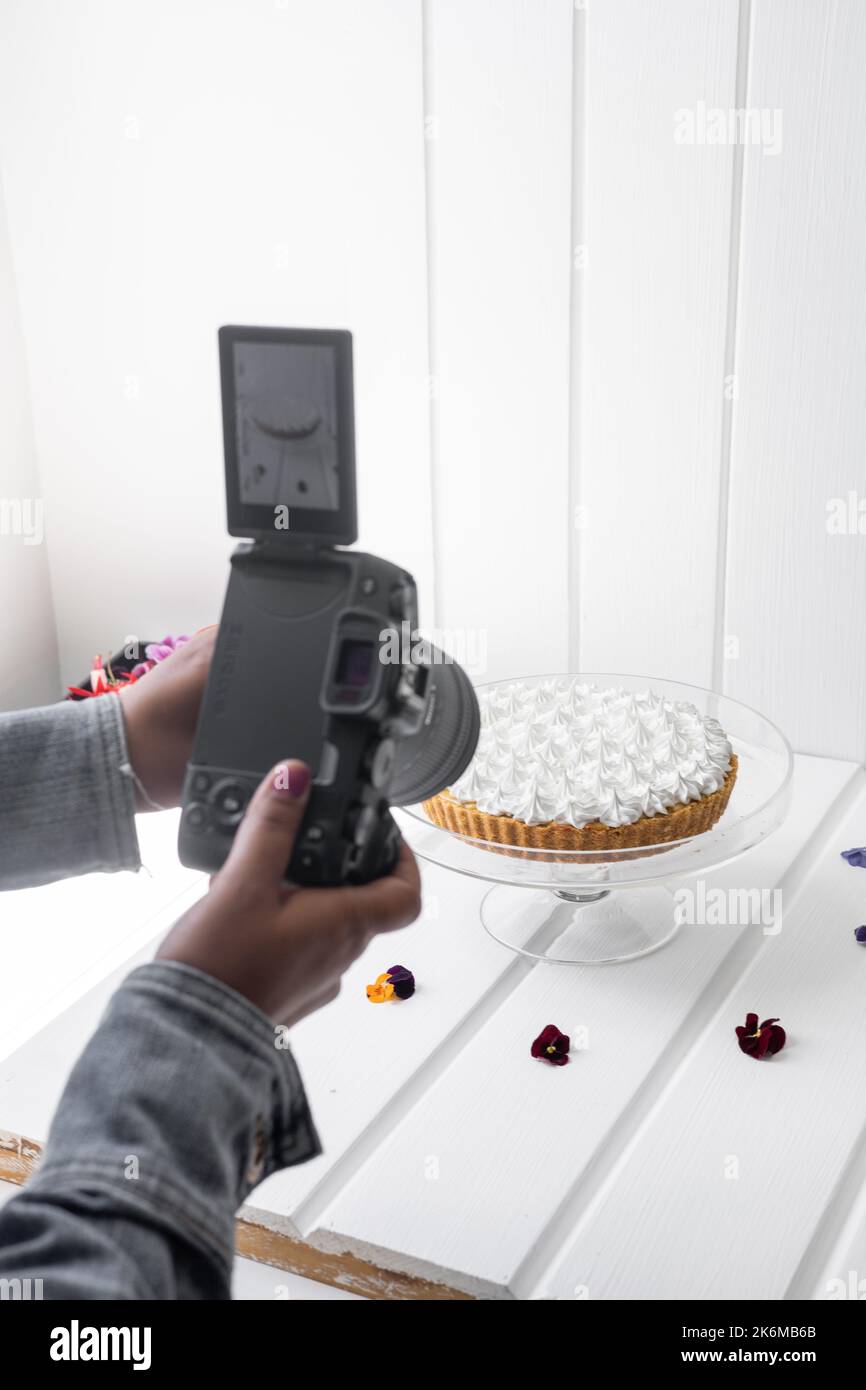 scattare foto di una torta decorata con crema con fotocamera professionale, cibo delizioso con zucchero, pasticceria in studio Foto Stock