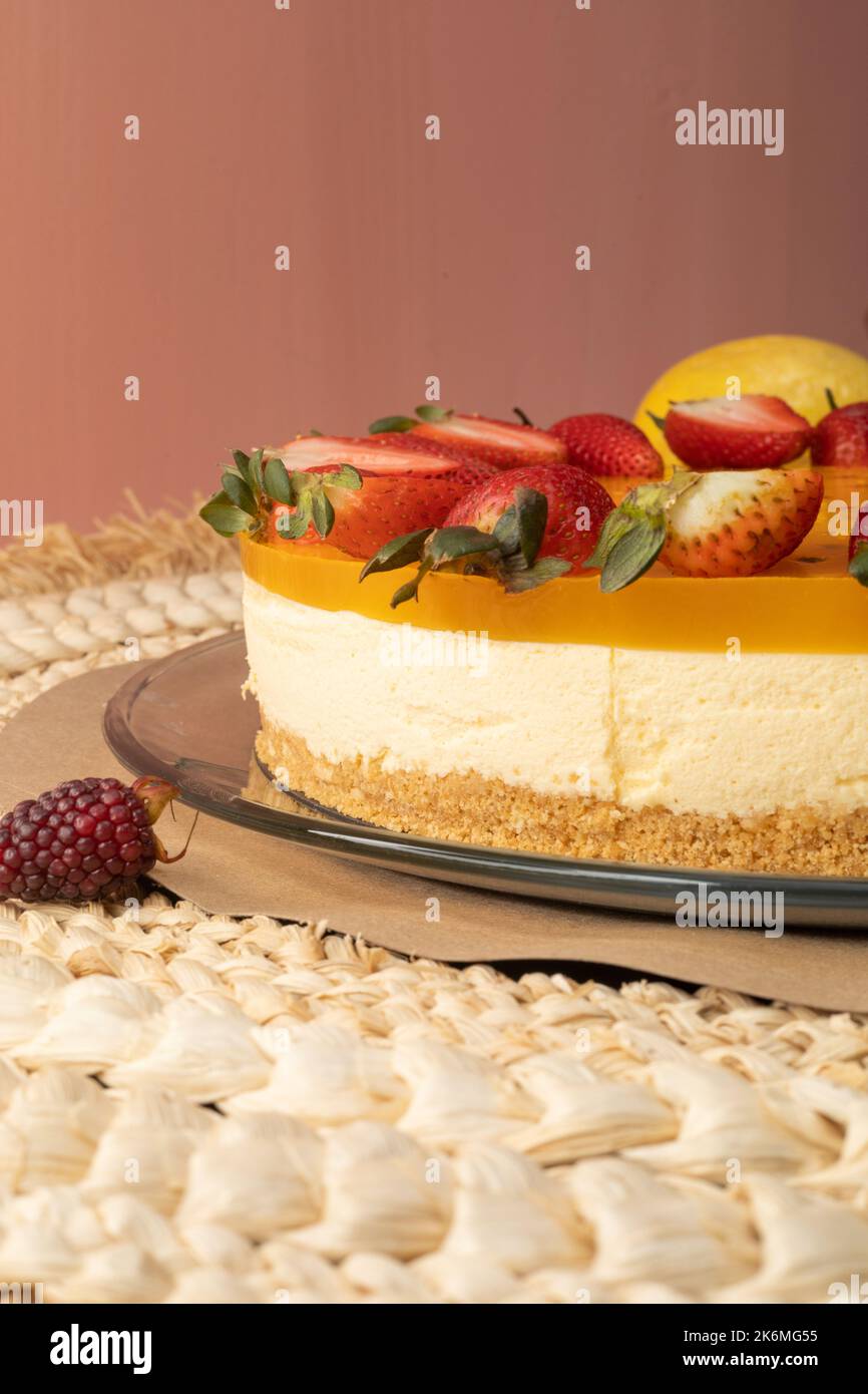 cheesecake appetitosa al frutto della passione decorata con crema e fragole, dessert pronto da mangiare, cibo dolce e stile gourmet, carta da parati Foto Stock