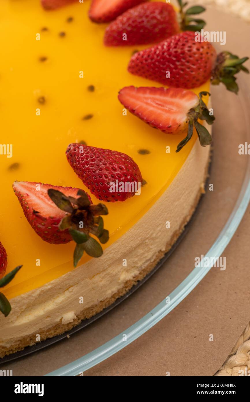 torta ricoperta di gelatina con frutto della passione decorata con fragole, dolce stile gourmet, prelibatezze appetitose in studio Foto Stock