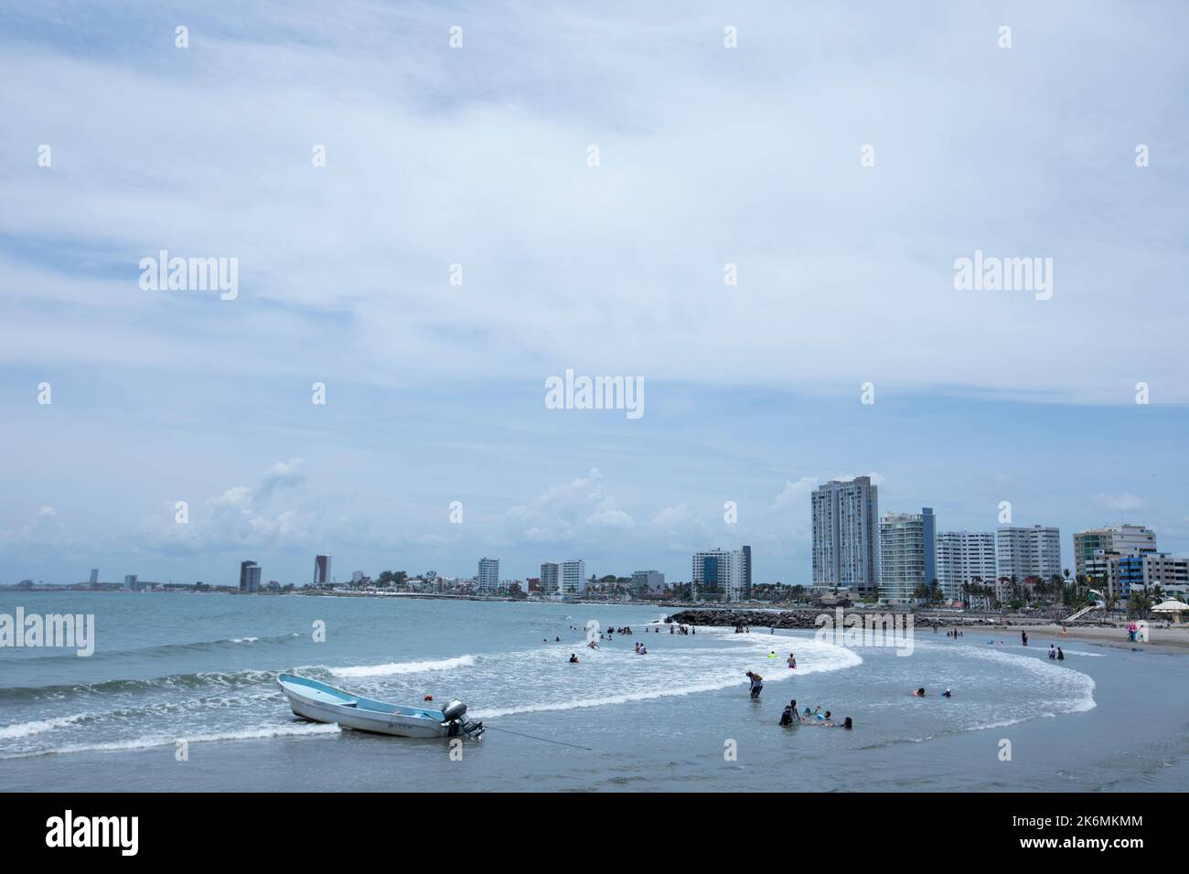 Boca del Rio, Veracruz, Messico - 23 luglio 2022: Le persone godono di una calda giornata estiva in una spiaggia incorniciata dallo skyline. Foto Stock