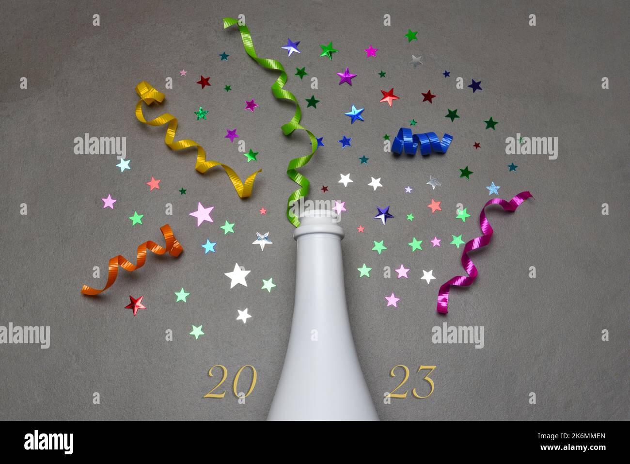 Concetto di nuovo anno 2023. Bottiglia di champagne piatto su piastrelle grigie con stelle colorate e nastro e la data 2023 Foto Stock