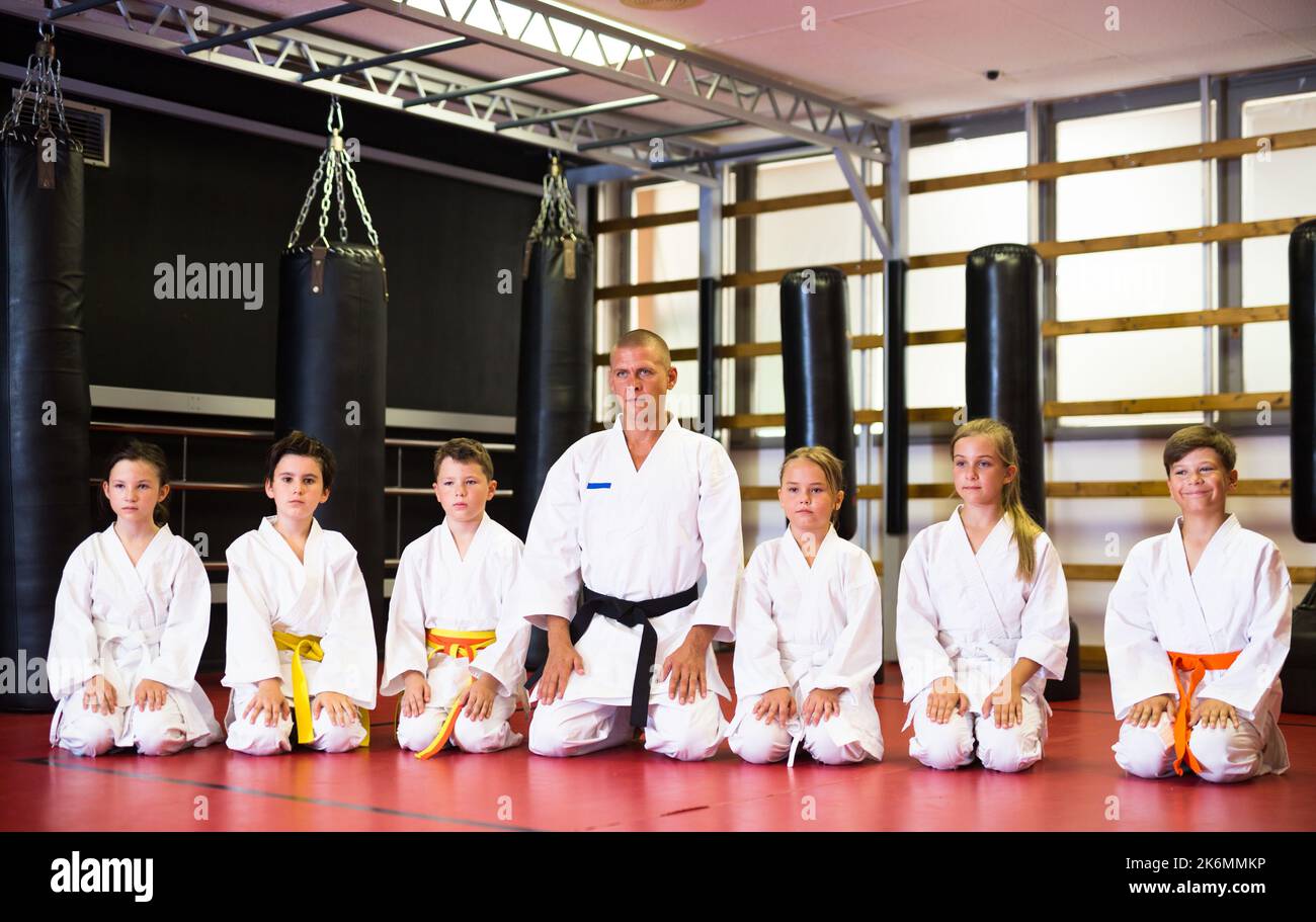 Bambini con il loro istruttore maschio che si pone in classe karate Foto Stock